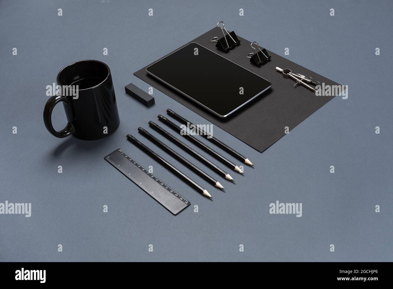 Flat lay of blank black paper sheet, black stationery items and coffee cup on gray desktop. Mock up Stock Photo