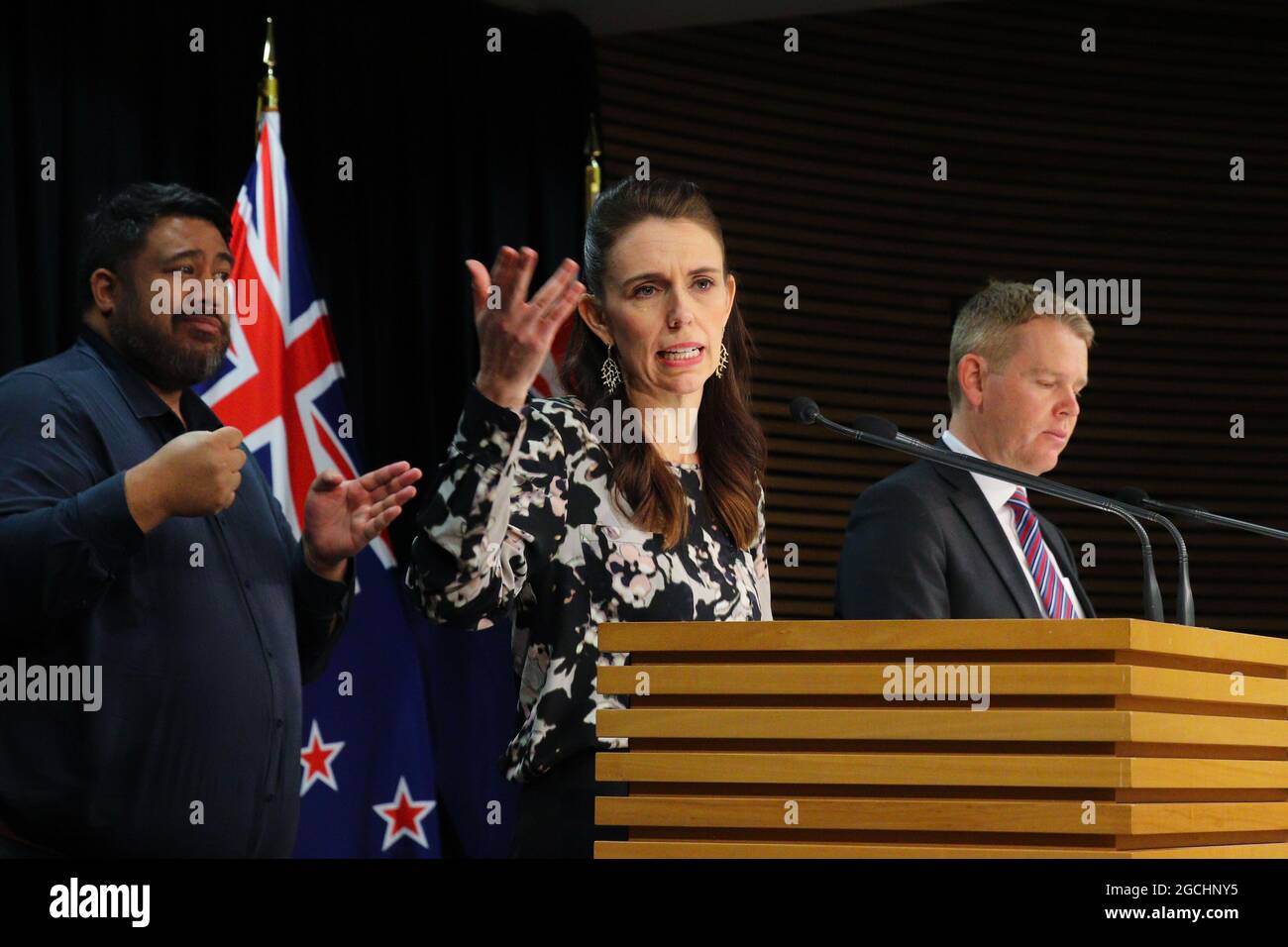 Wellington, New Zealand, 9 August 2021. New Zealand Prime Minister Jacinda Ardern, flanked by a sign language interpreter and Covid Response Minister Chris Hipkins (right) holds a press conference to discuss the exposure of unvaccinated port workers to crew infected with Covid-19 on board the Maersk cargo ship Rio de la Plata. Ardern expressed frustration over vaccine hesitancy related to online misinformation, and announced vaccination will be made mandatory for frontline port workers. Credit: Lynn Grieveson/Alamy Live News Stock Photo
