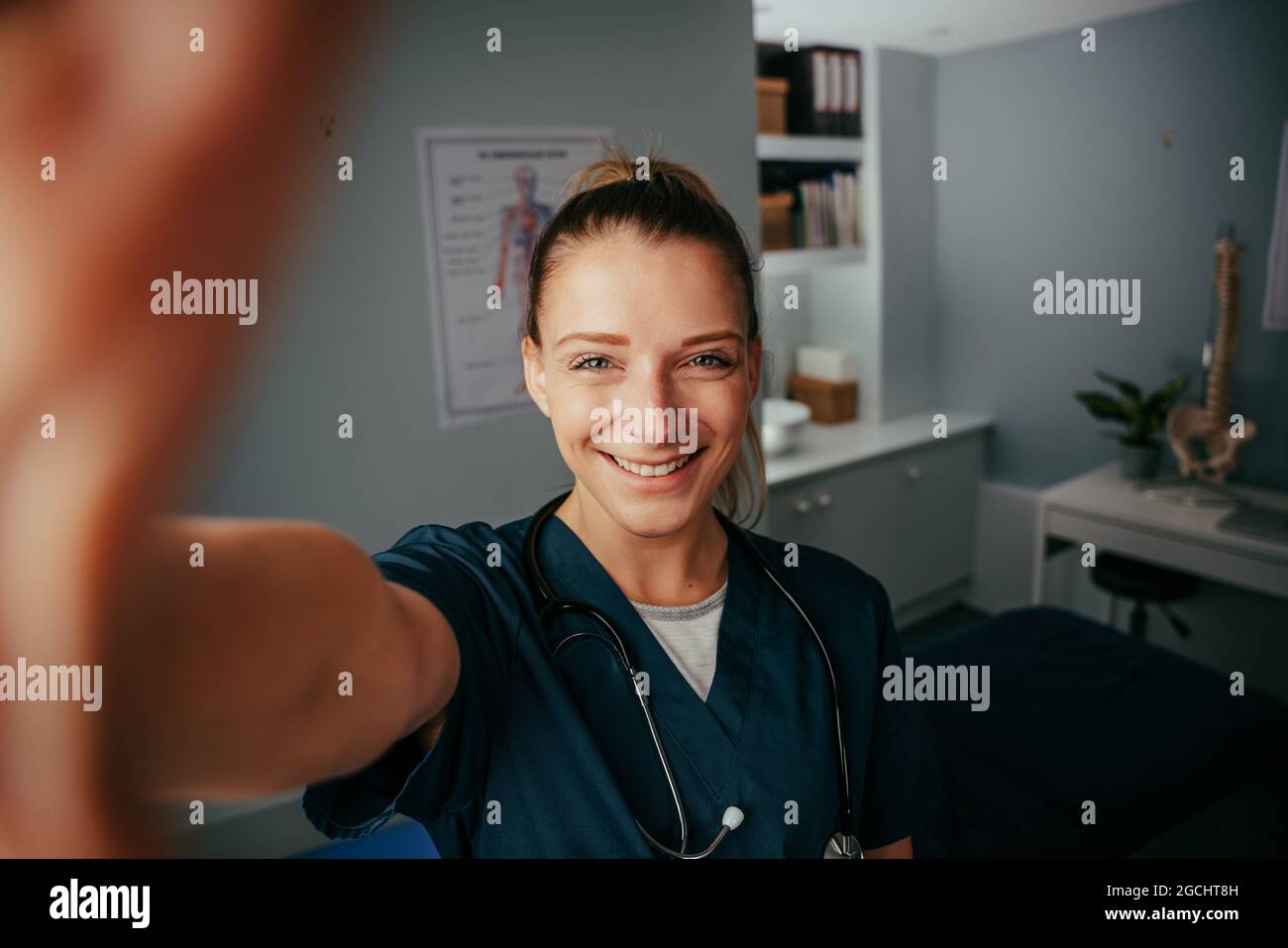 Caucasian female doctor taking selfie in doctors office with cellular device Stock Photo