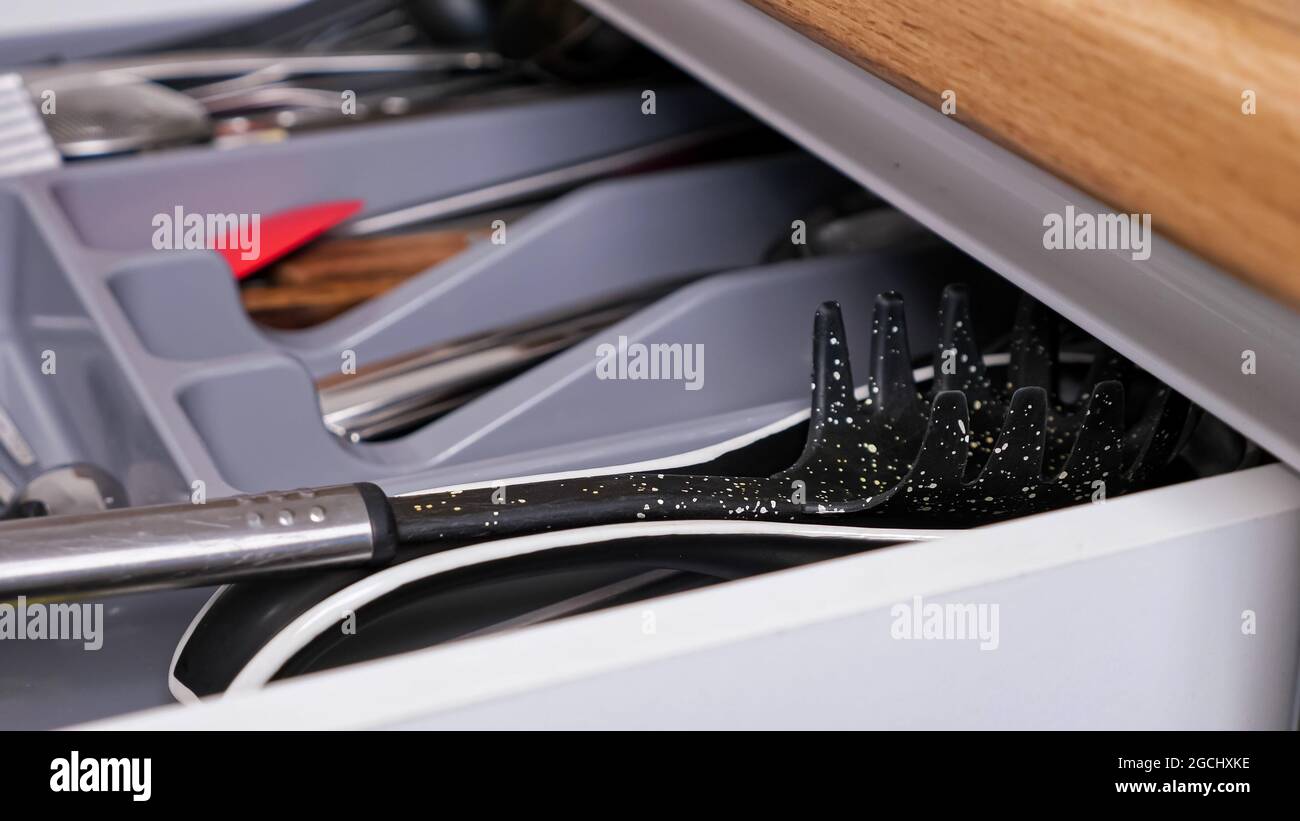 Person closes pull-out kitchen cabinet drawer with utensils Stock Photo ...