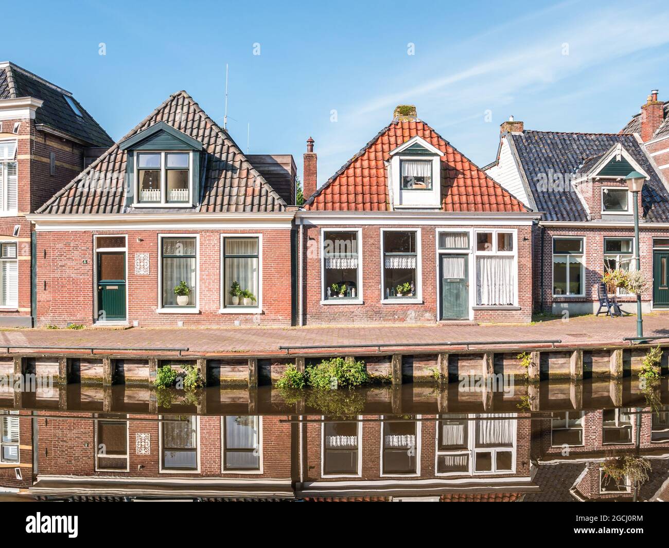 Houses reflecting in calm water of Wargaastervaart canal in Wergea, Leeuwarden, Friesland, Netherlands Stock Photo