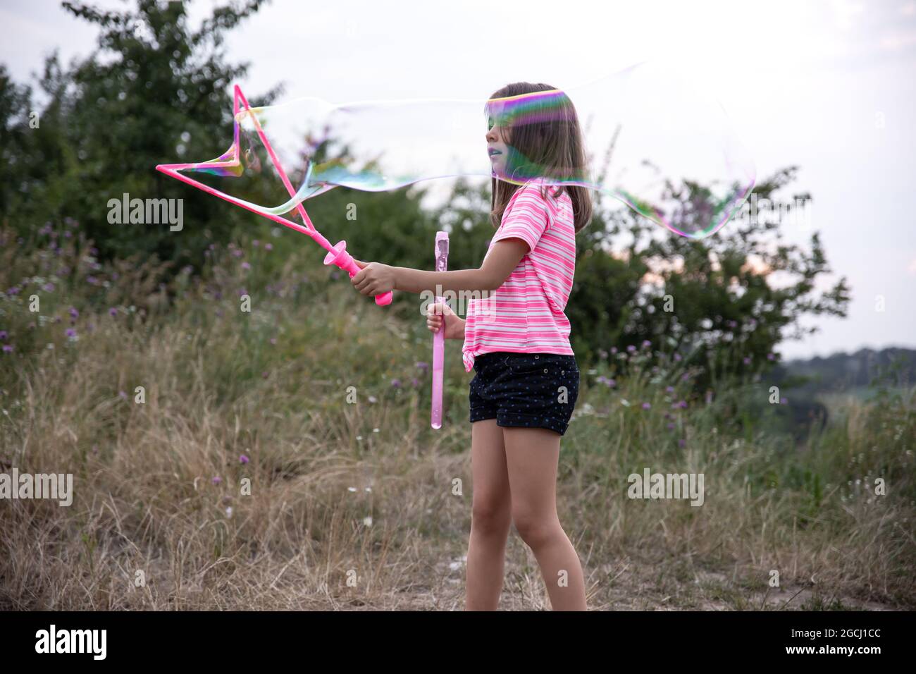 A little girl in nature plays with big soap bubbles Stock Photo - Alamy