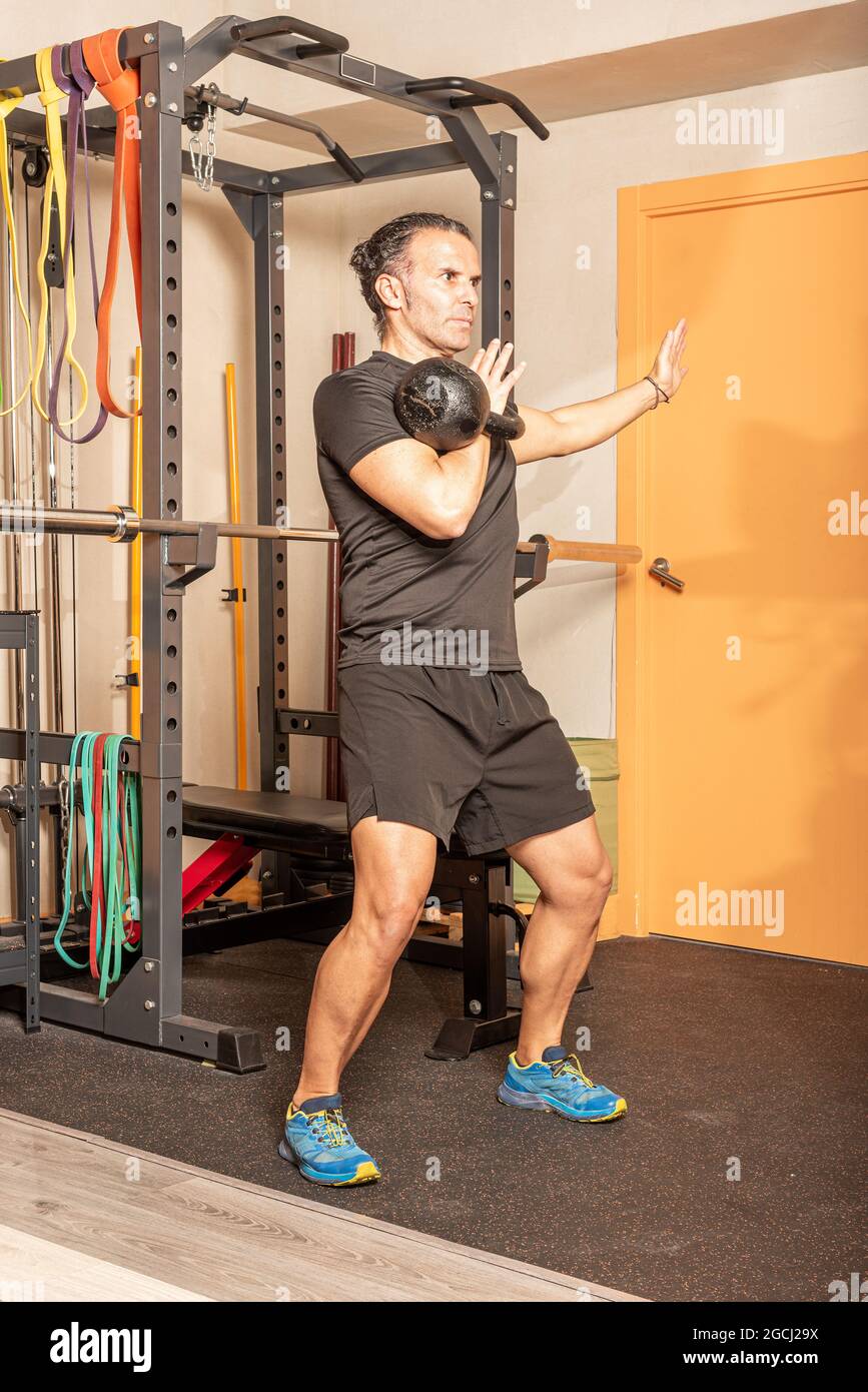 Man doing shoulder press with kettlebell in gym Stock Photo