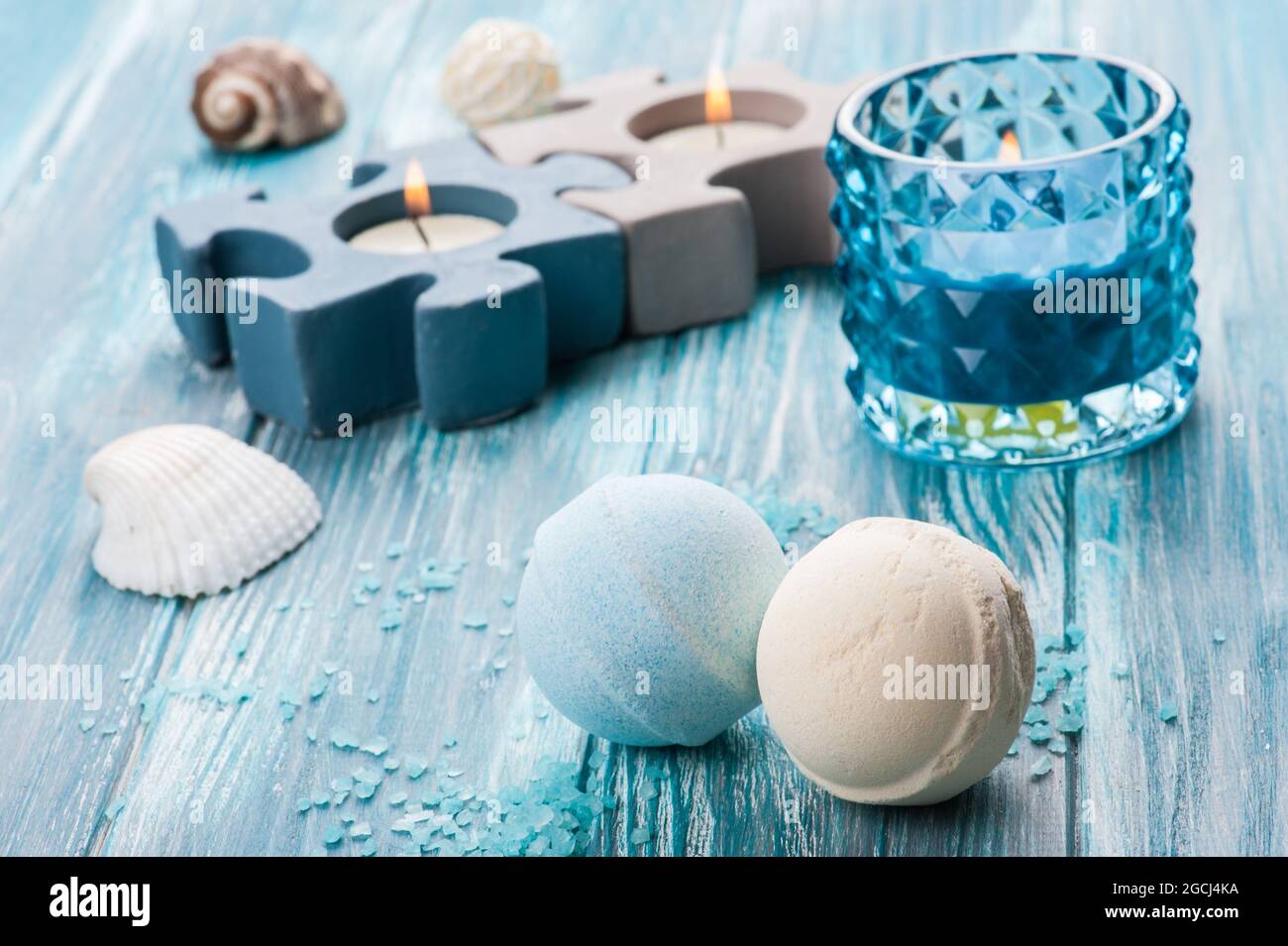 SPA still life, closeup of blue lit candle and bath bombs on wooden background Stock Photo