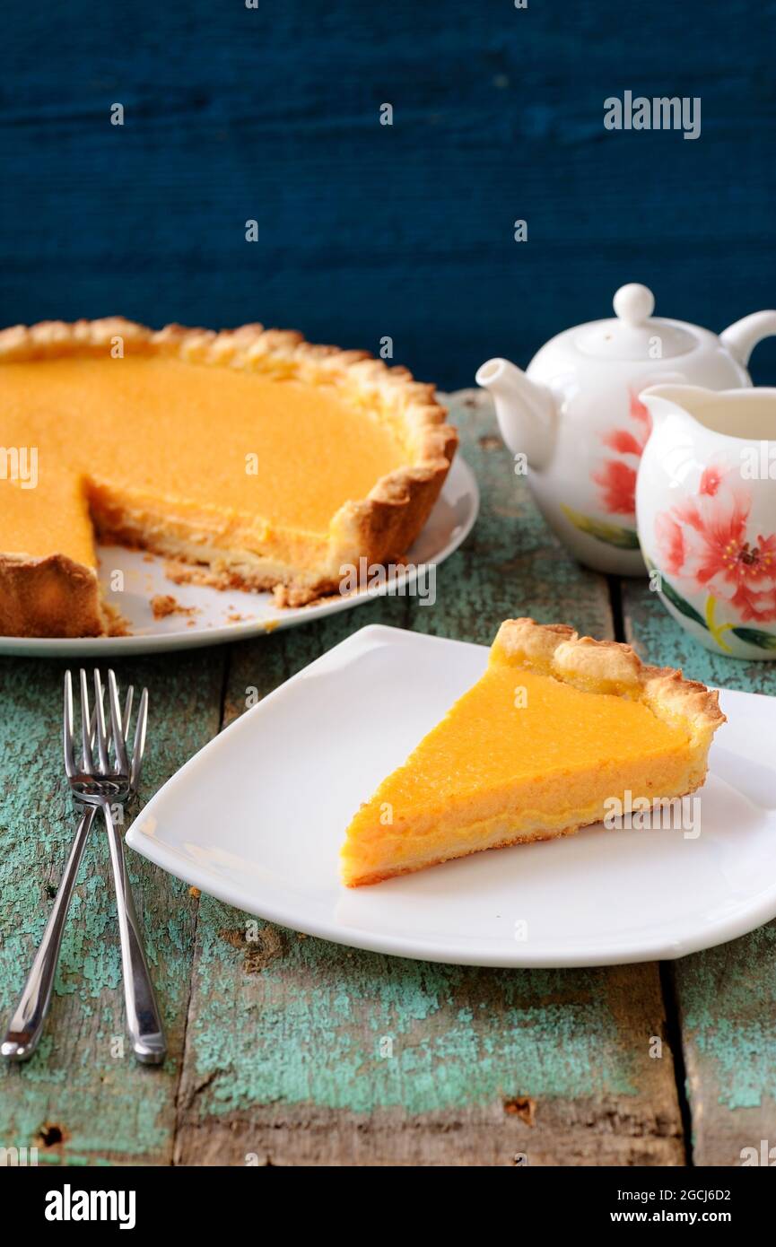 Homemade bright pumpkin pie and teaware on shabby wooden table vertical Stock Photo