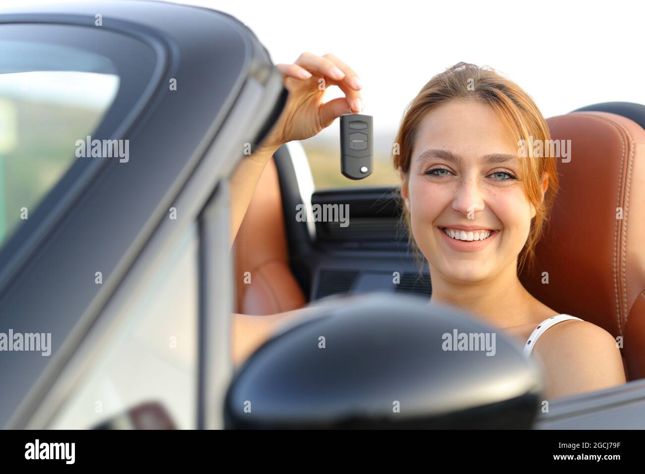 Happy convertible car owner showing keys to camera Stock Photo