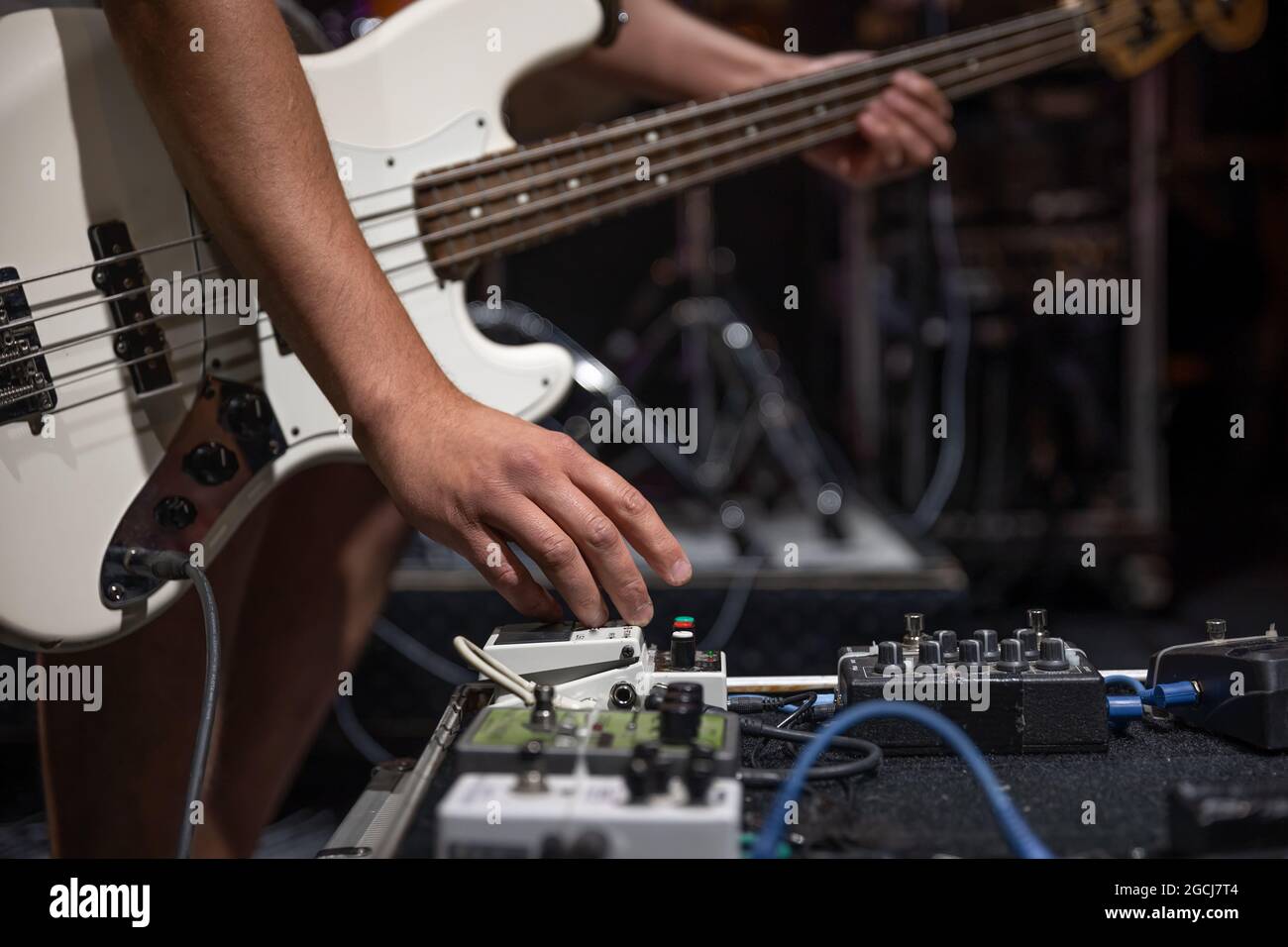 A male guitarist setting up guitar audio processing effects on stage