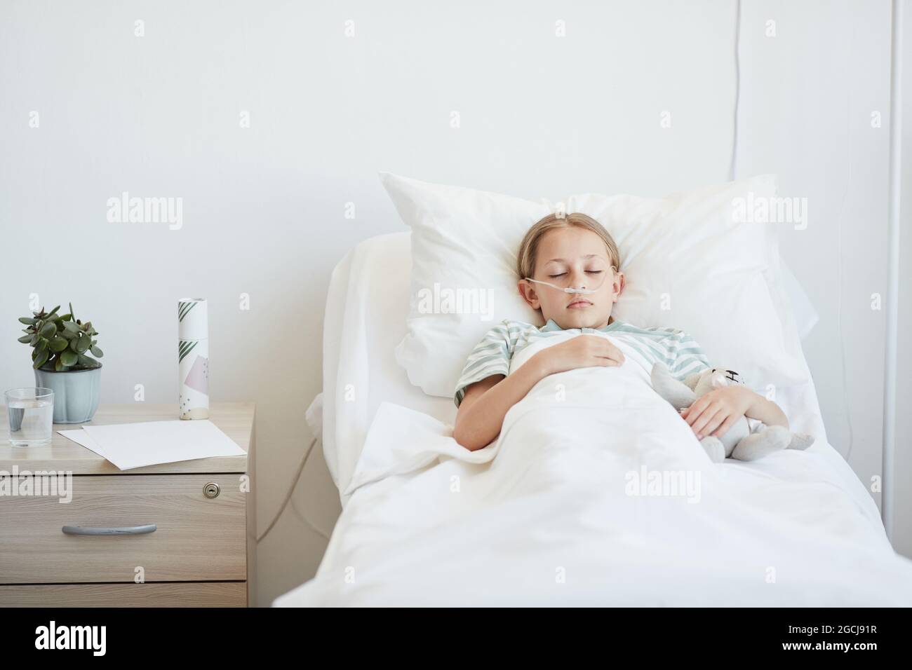Portrait of little girl laying in hospital bed with oxygen support, copy space Stock Photo