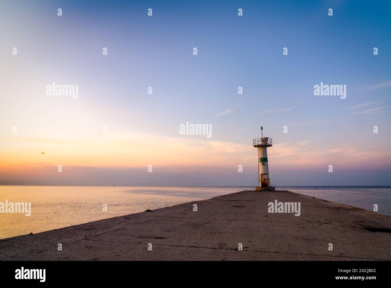 view of white lighthouse with breakwater. Sunrise in Mediterranean sea. . High quality photo Stock Photo