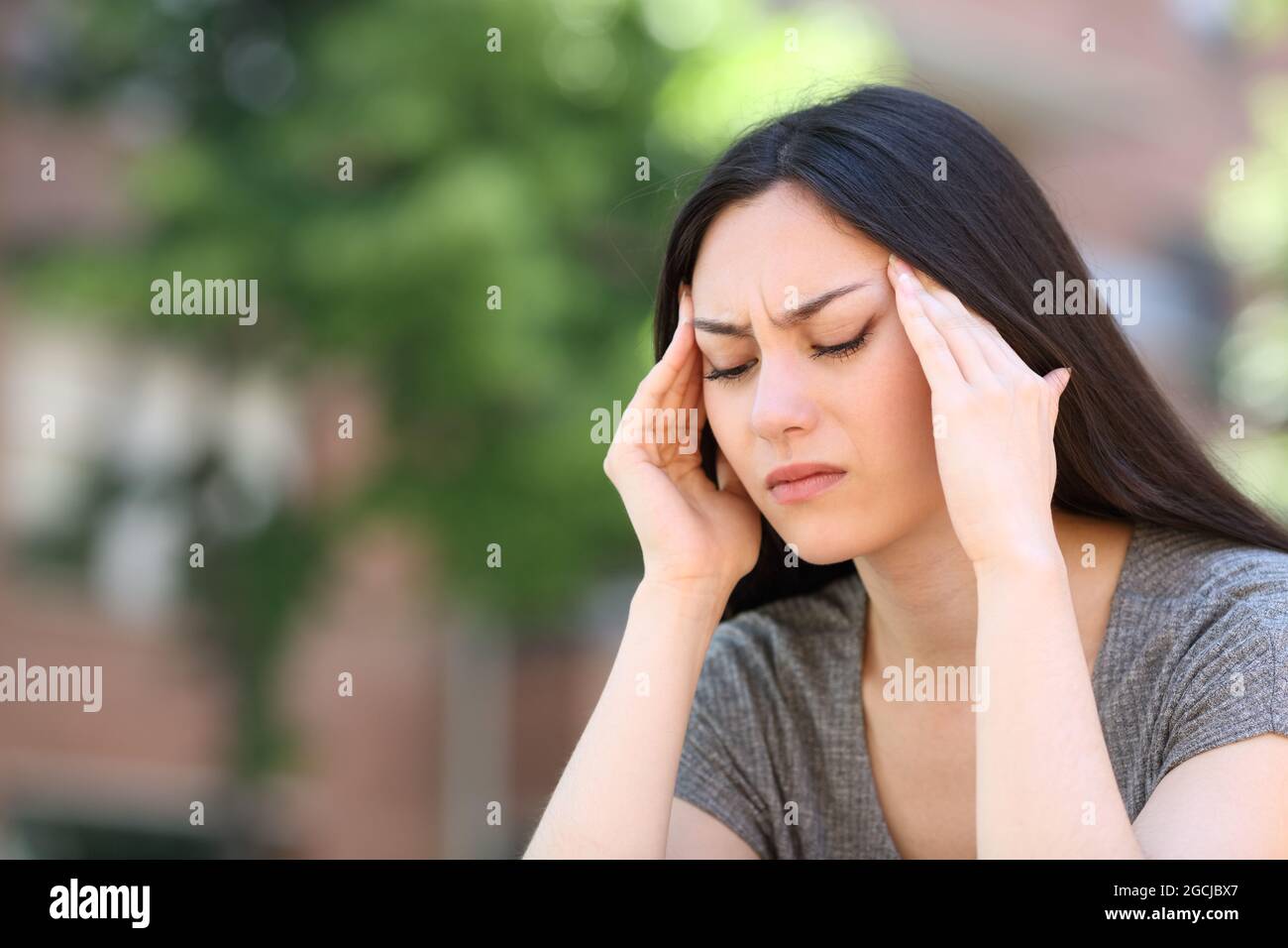 Asian woman suffering migraine attack complaining in the street Stock Photo