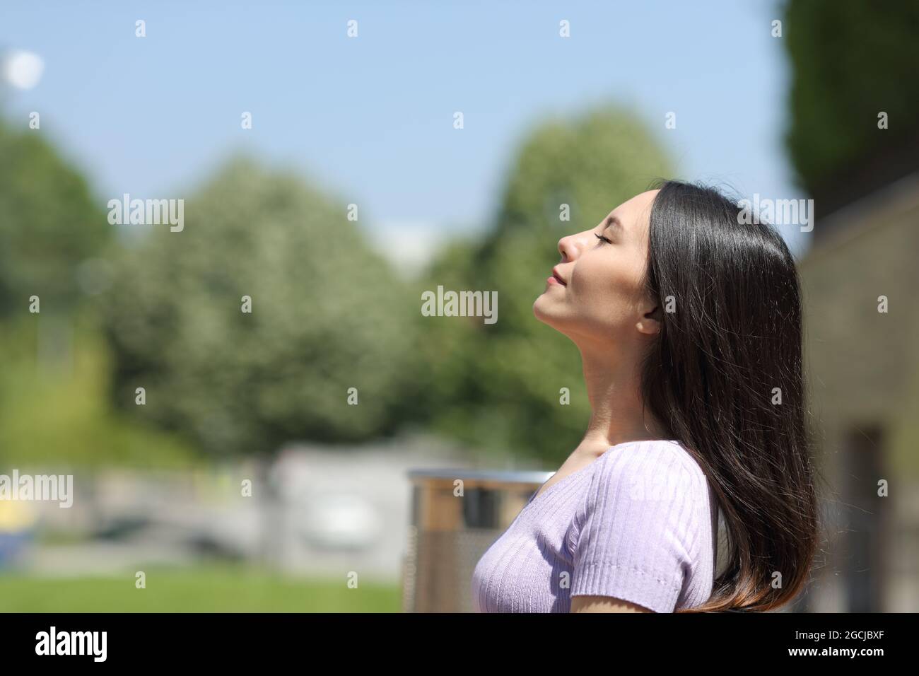 Profile of an asian woman breathing fresh air in a park a sunny day ...