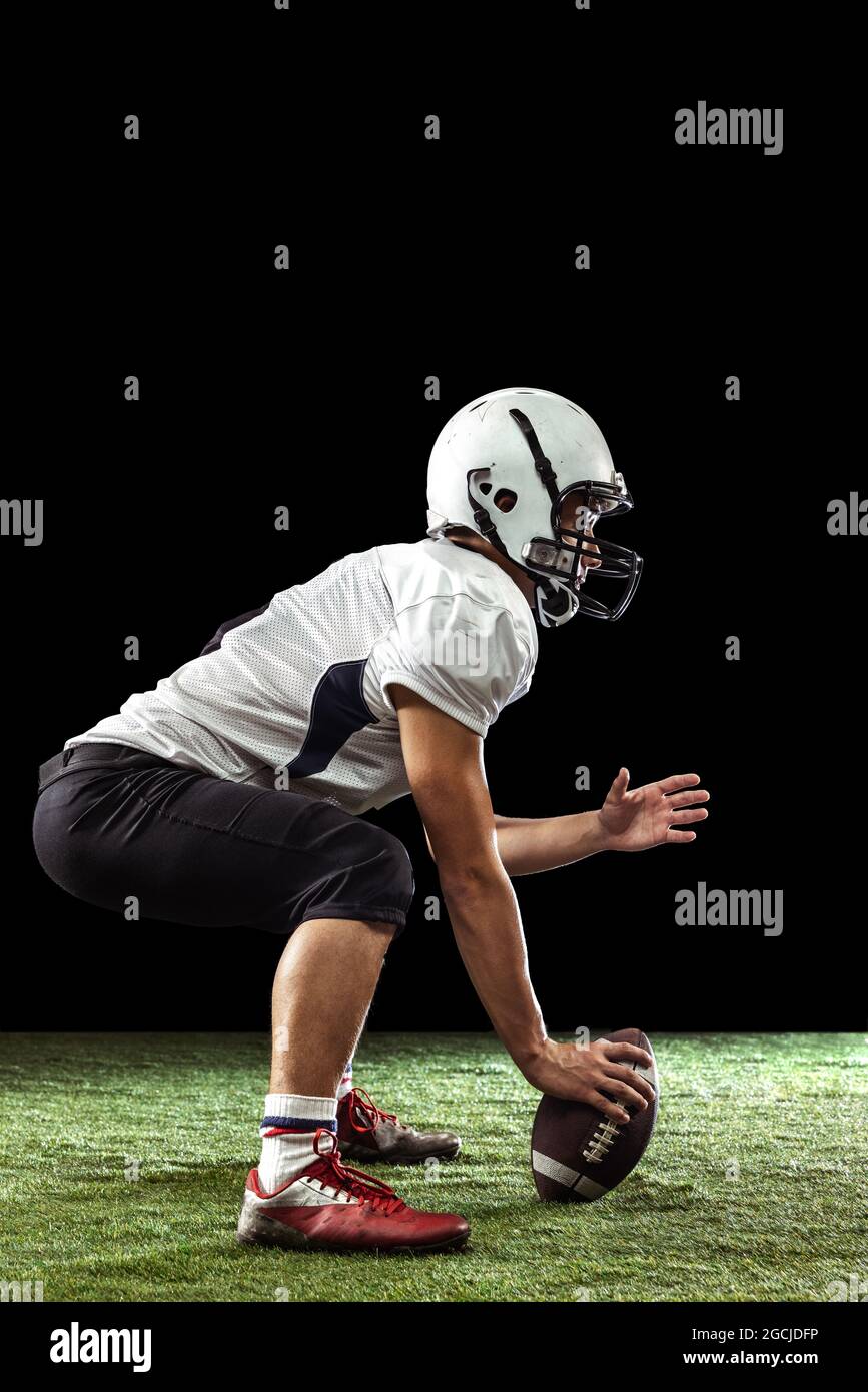 Portrait of American football player training isolated on dark studio ...