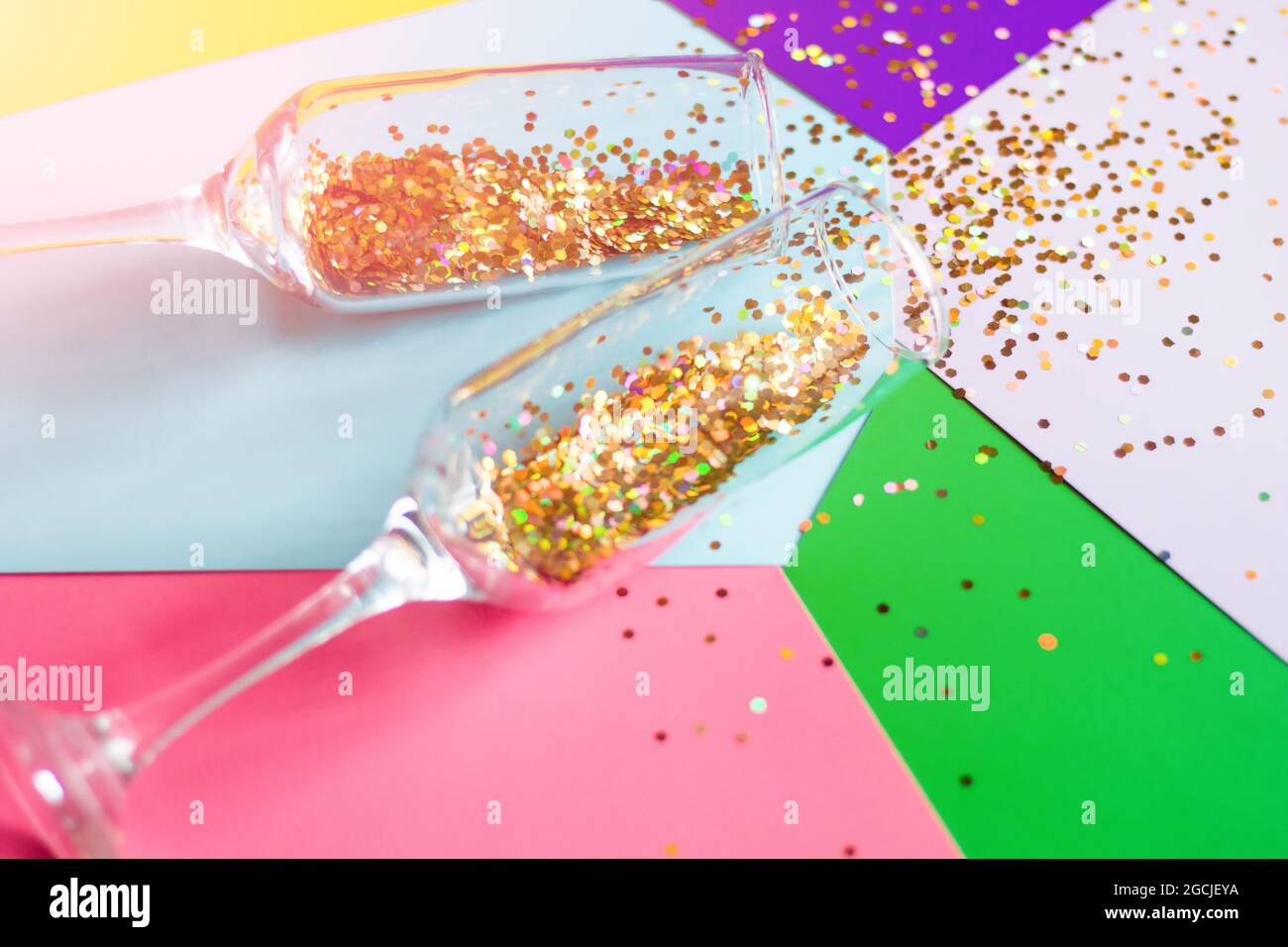 champagne glasses with confetti on a colored background close-up
