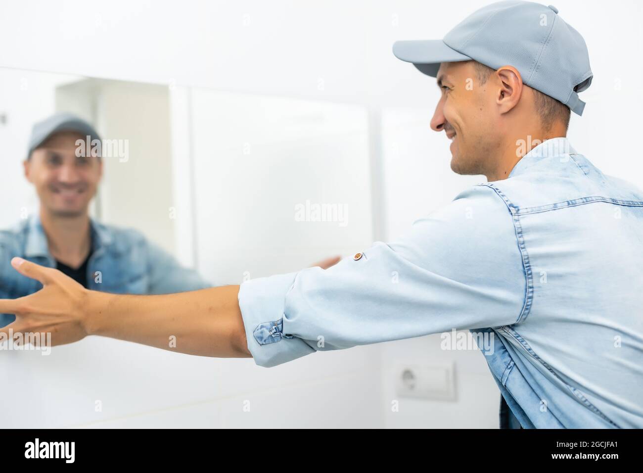Handyman installing mirror in bathroom Stock Photo Alamy