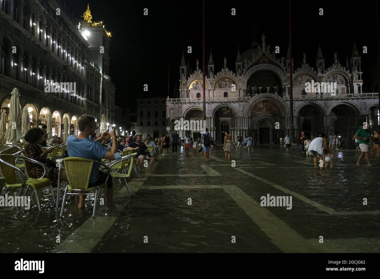 People sit at a cafe in a flooded St. Mark's Square during an exceptional high water in Venice, Italy August 8, 2021.(MvS) Stock Photo