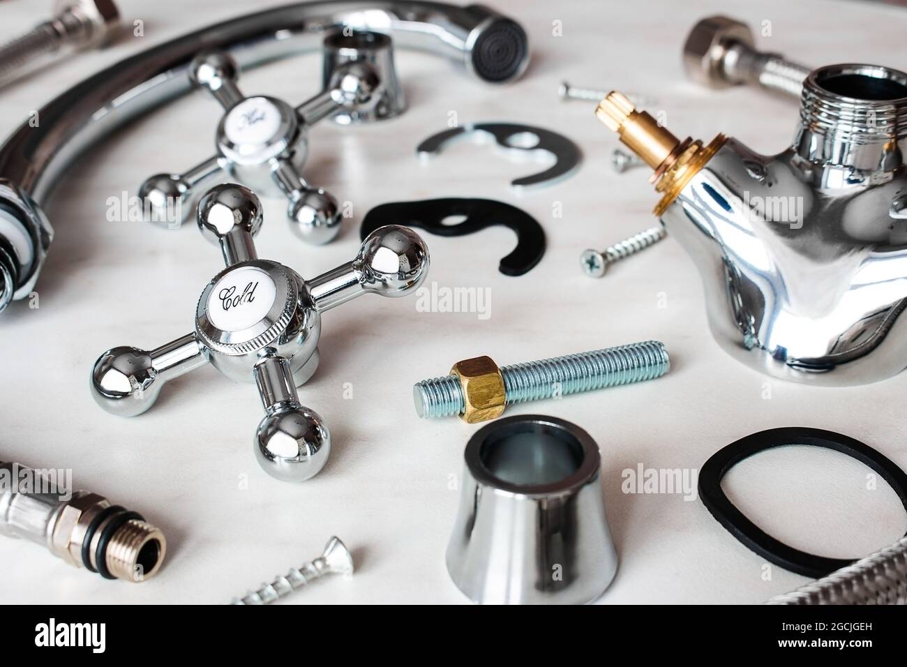 plumbing bolts, gaskets, parts of a disassembled water tap on a white