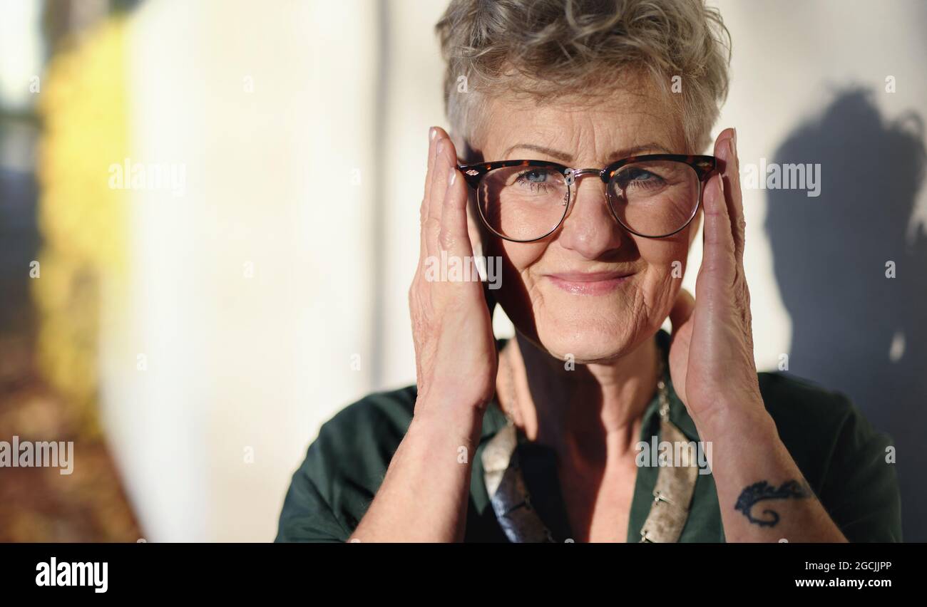 Portrait of senior woman standing outdoors in town, looking at camera ...