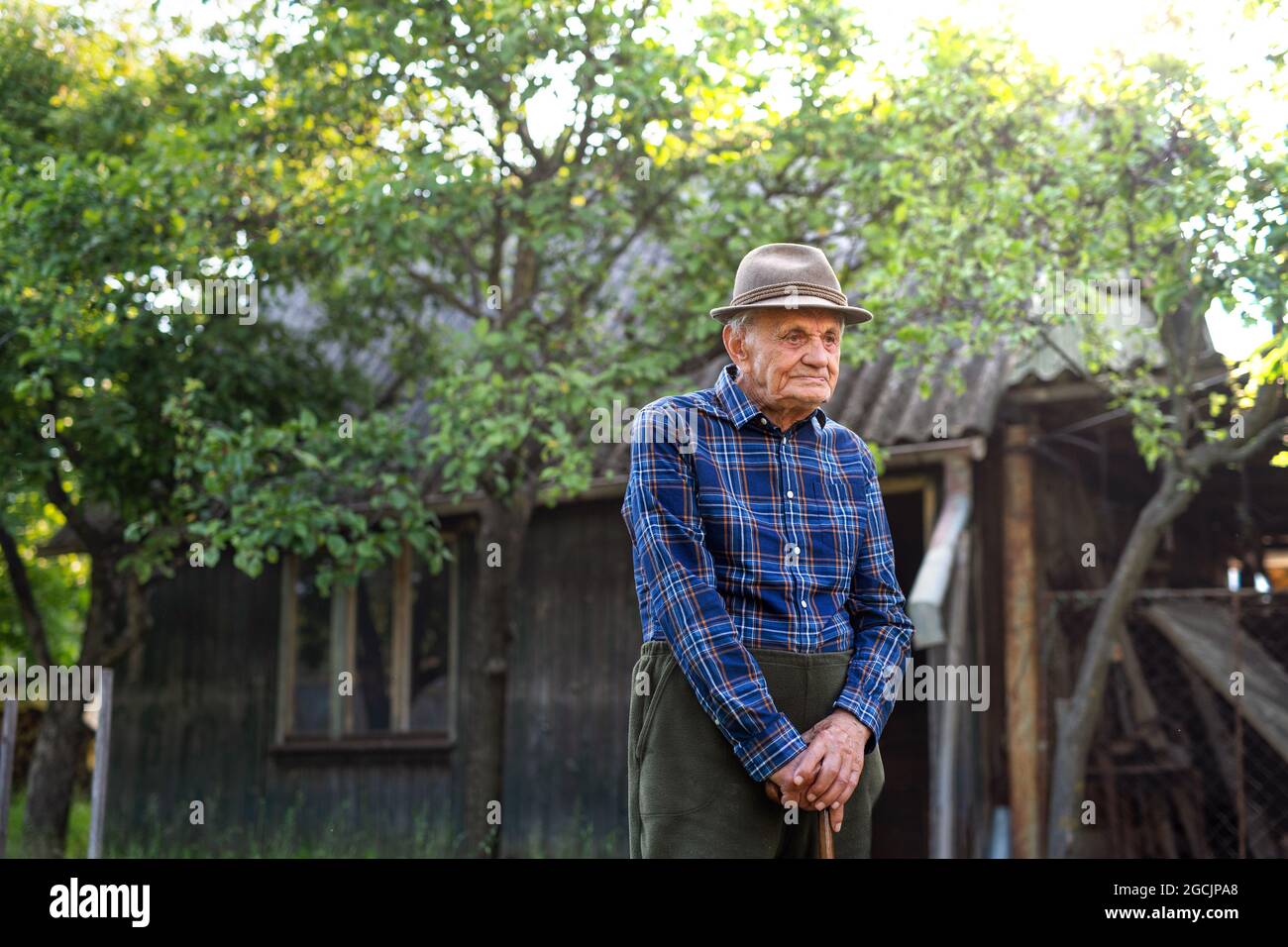 Portrait of elderly man standing outdoors in garden, resting. Stock Photo