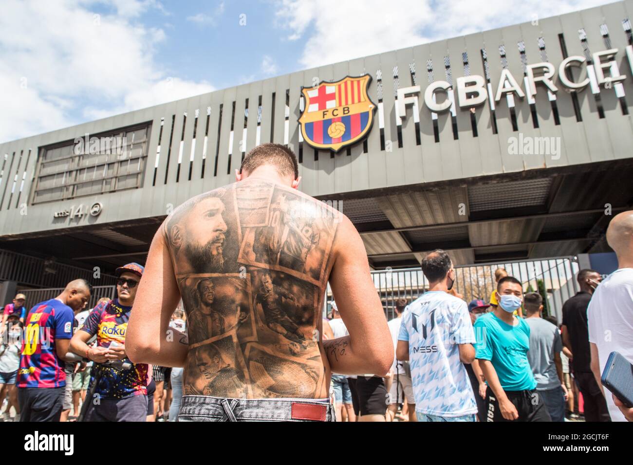Barcelona, Catalonia, Spain. 8th Aug, 2021. Lionel Messi fan with a tattoo on his back with the face of Messi and other idols of FC Barcelona, such as Ronaldinho (Ronaldo de Assis) and Andres Iniesta is seen at the Camp Nou stadium gate.Lionel Messi fan with a FC Barcelona Messi 10 shirt is seen at the gate of Camp Nou stadium.Lionel Messi fans are seen with FC Barcelona's Messi 10 shirt at the Camp Nou stadium gate.At the time of the press conference of farewell to Lionel Messi from Futbol Club Barcelona, fans of the player were at the door of the Camp Nou stadium to try to say goodbye to Stock Photo