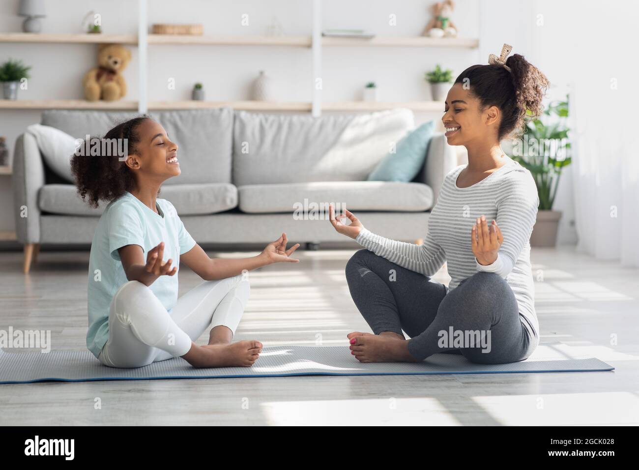 Sporty black family mother and daughter meditating at home Stock Photo ...