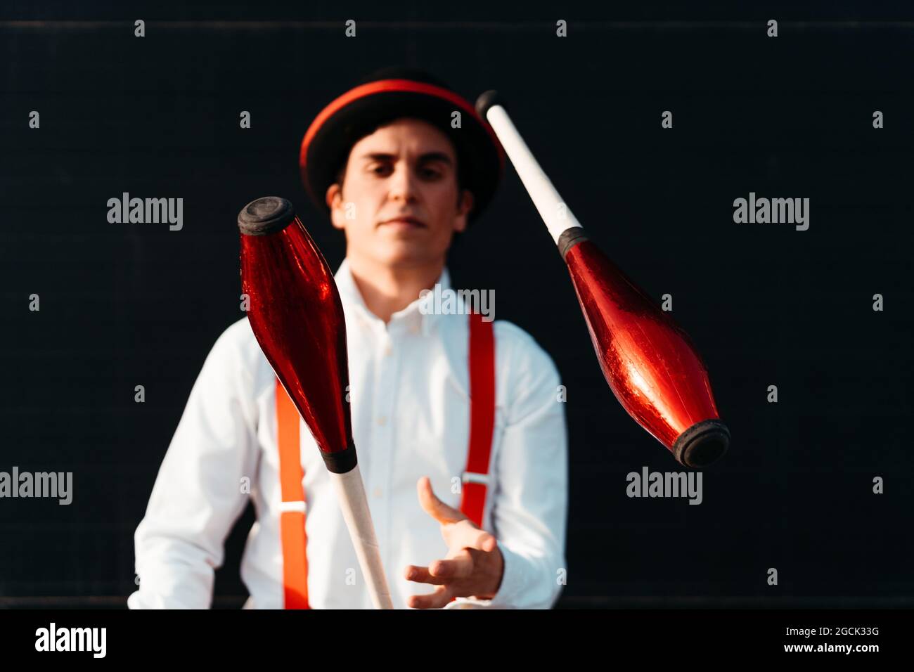 Skilled young male circus performer juggling with club on modern building Stock Photo