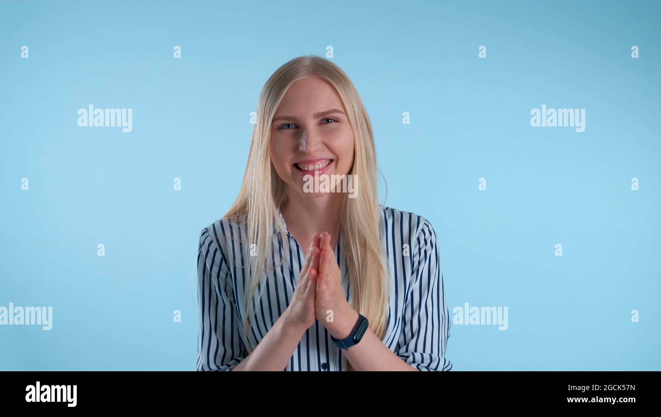 Portrait of smiling young lady giving applause to somebody on blue background. She clapping her hands. Stock Photo