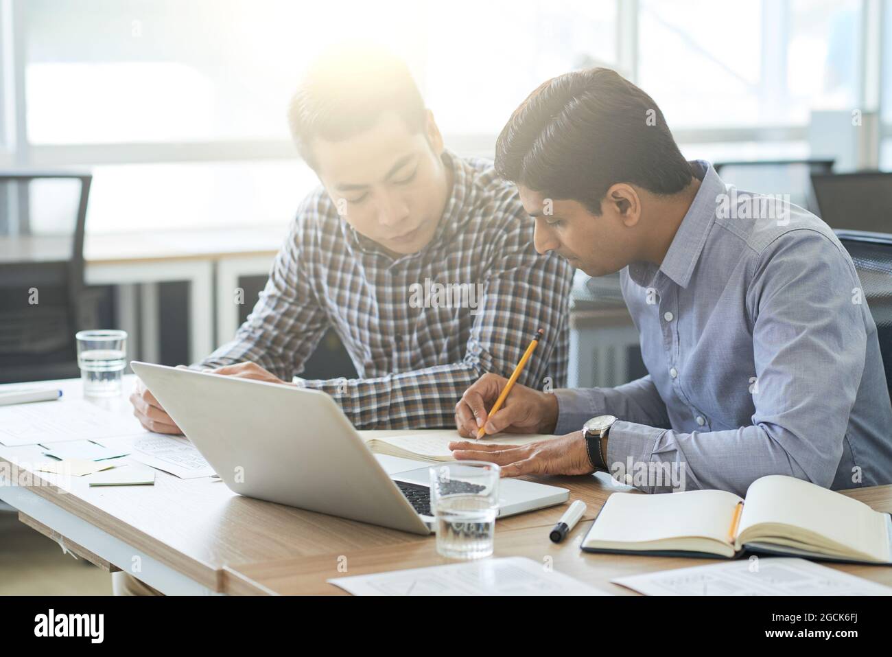 Multi-ethnic business team discussing documents with interface layouts at meeting Stock Photo