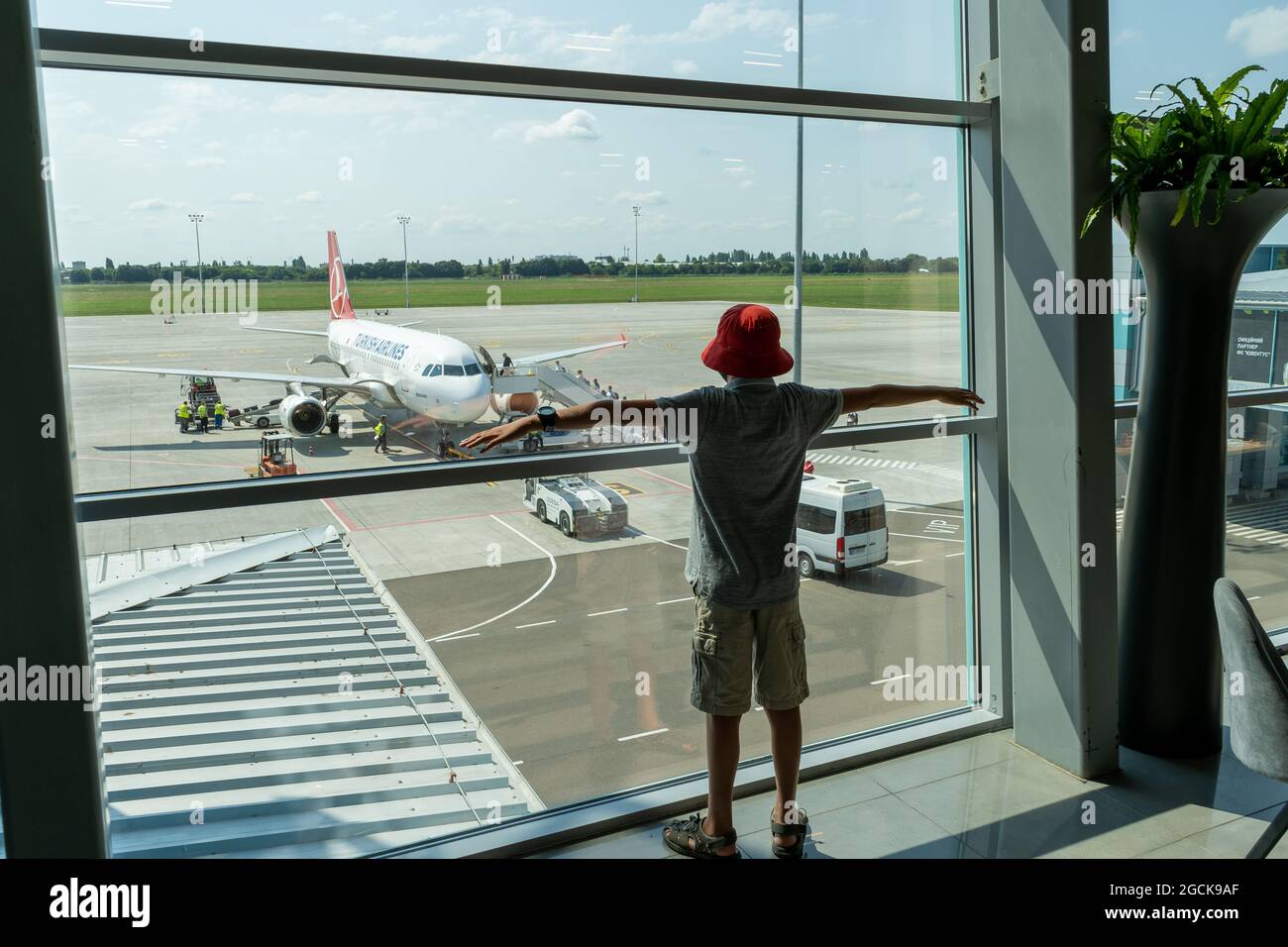 Ukraine, Odessa - August 3, 2021: At the ODS airport await departure. The plane is outside the window. A child is looking at the plane through the Stock Photo