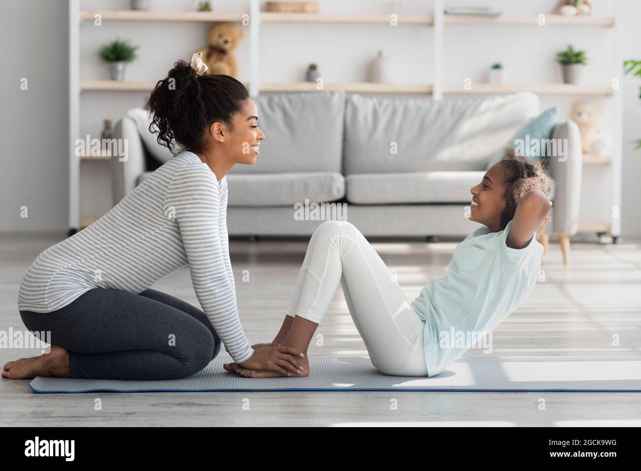 Black mother and daughter in sportswear exercising together Stock Photo ...