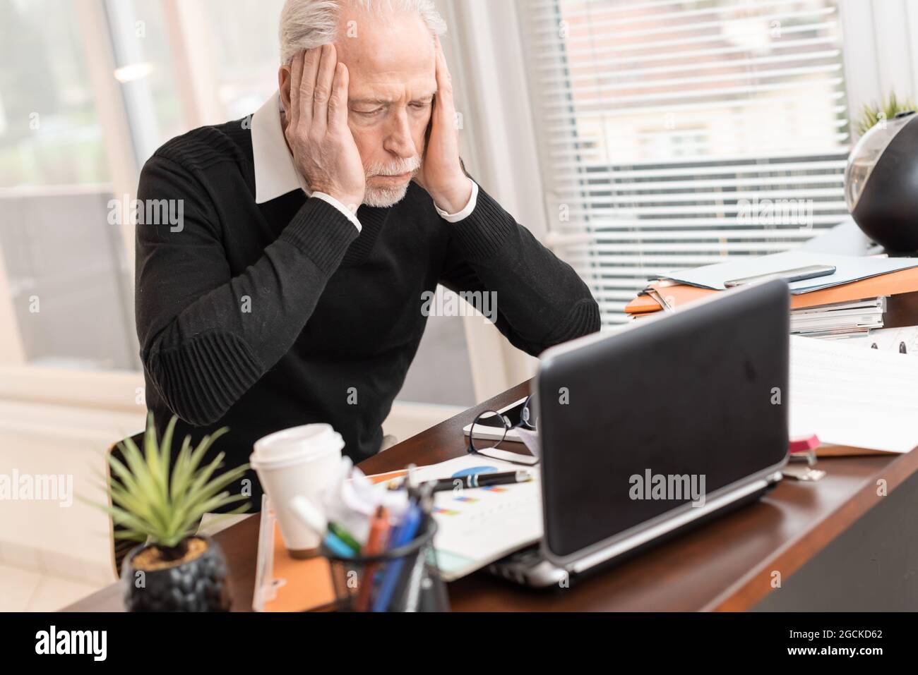 Overworked businessman sitting at a messy desk in office Stock Photo ...