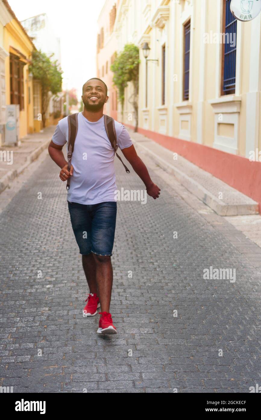 Smiling man with backpack looking upward while standing outdoors Stock Photo
