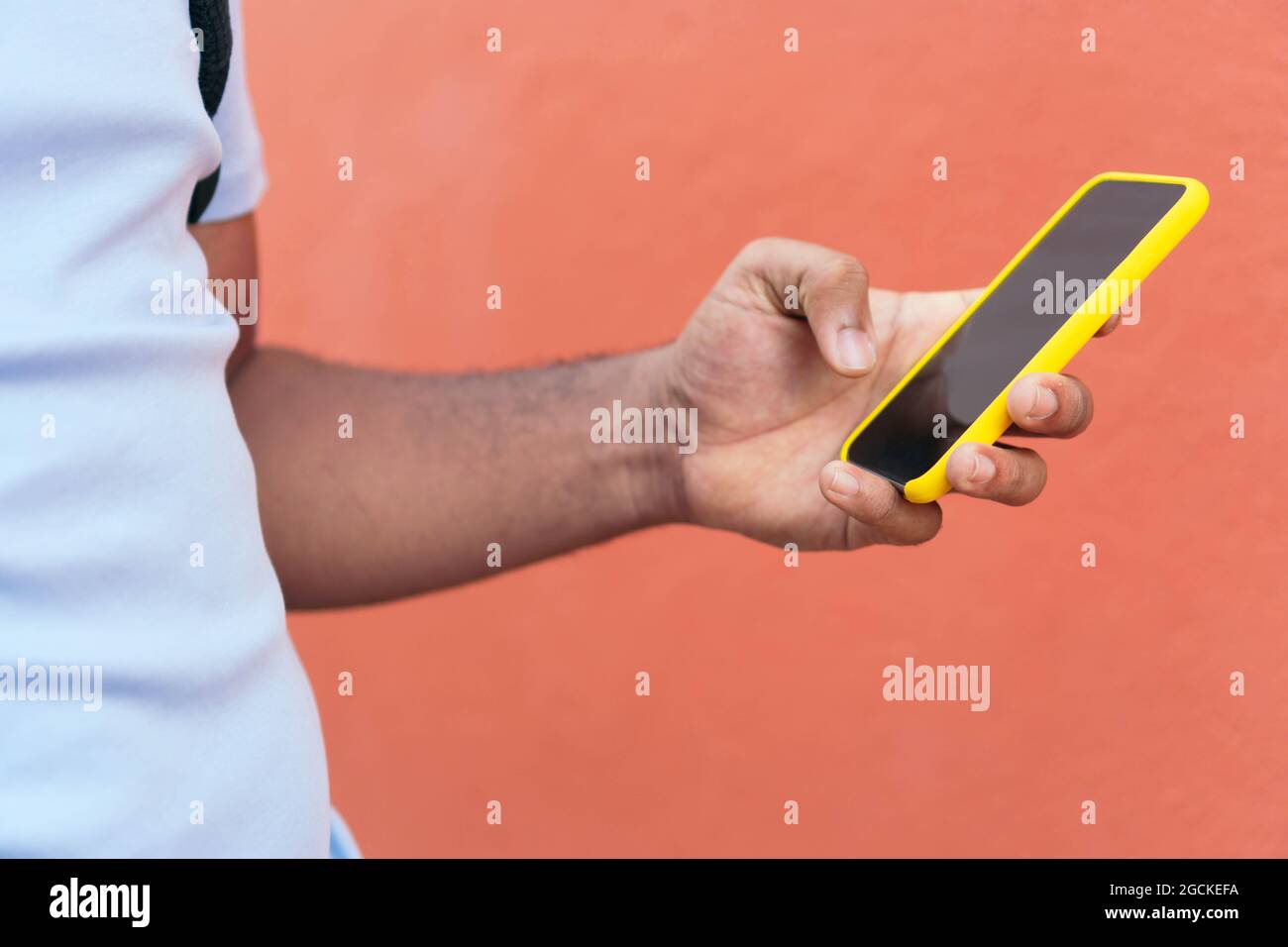 Young man with smart phone next to a red wall Stock Photo