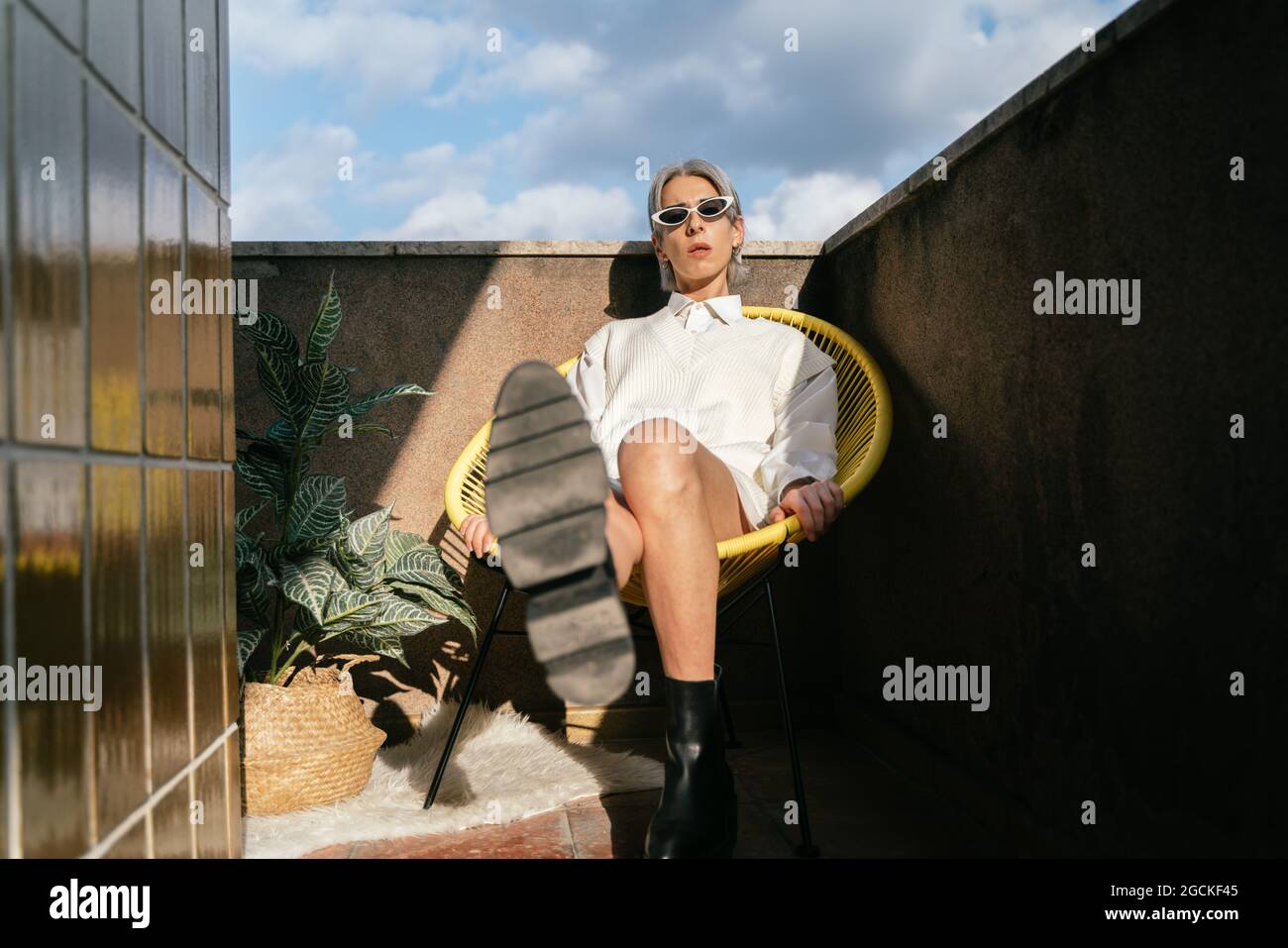 Confident transgender female in trendy outfit reaching out leg to