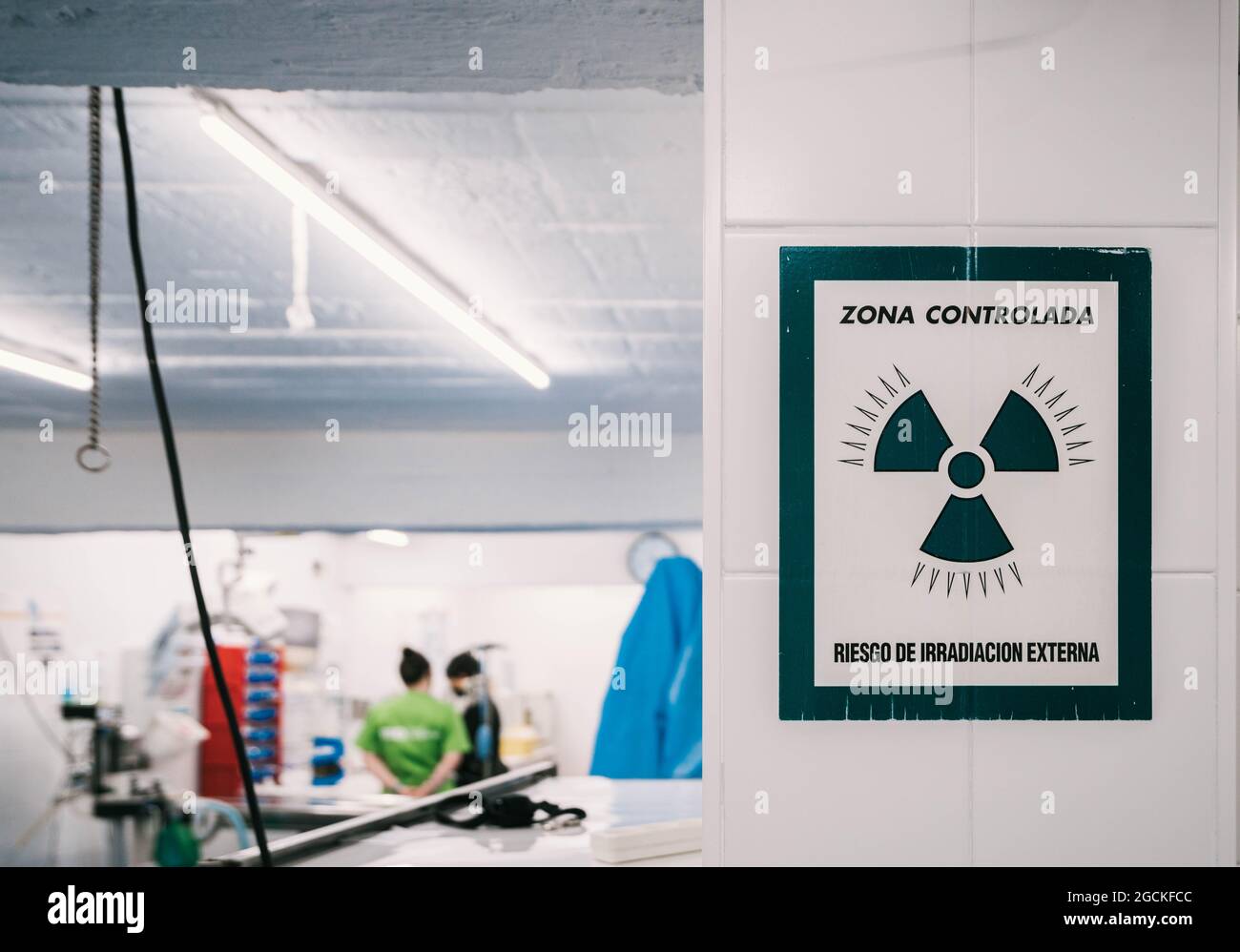 Warning sign of danger radioactive zone hanging on wall near entrance of X ray laboratory in vet clinic with people working inside Stock Photo