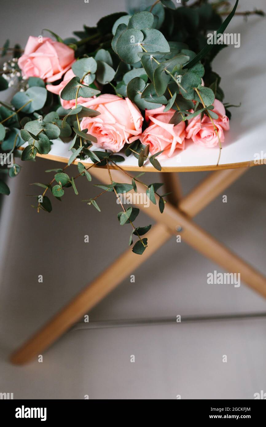 From above pink roses bouquet with green leaves lying on table Stock Photo