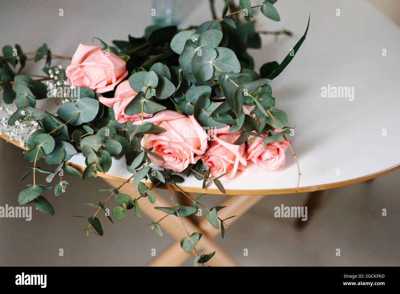 From above pink roses bouquet with green leaves lying on table Stock Photo