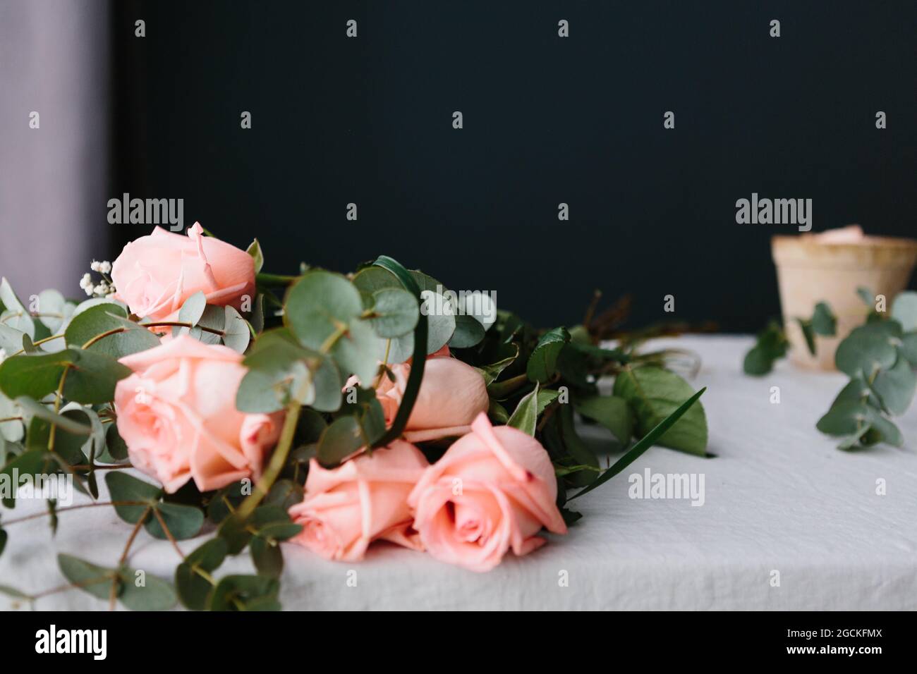 Pink roses bouquet with green leaves lying on white table Stock Photo