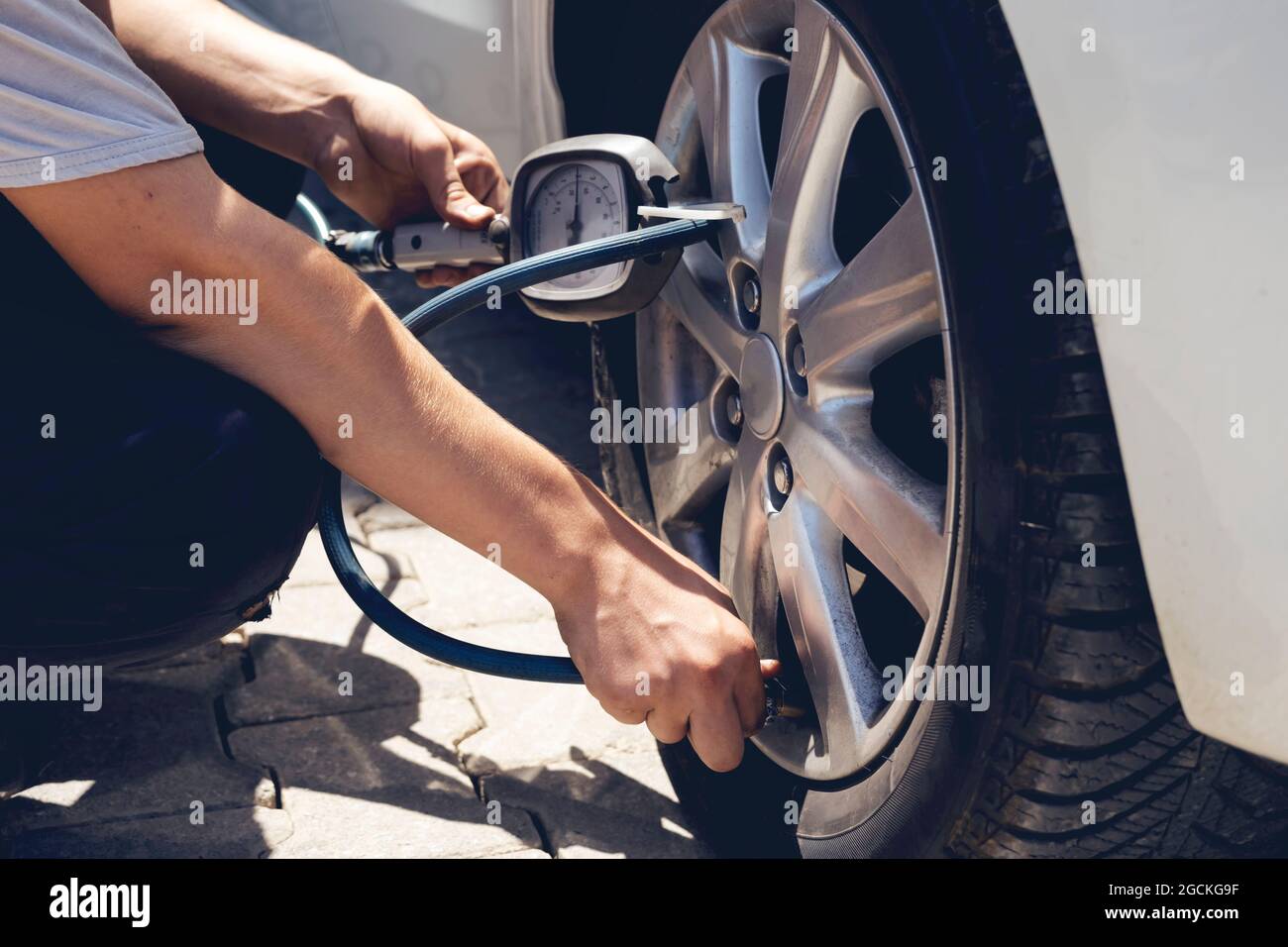 Close up mechanic inflating tire hand holding gauge pressure for checking and filling air in car