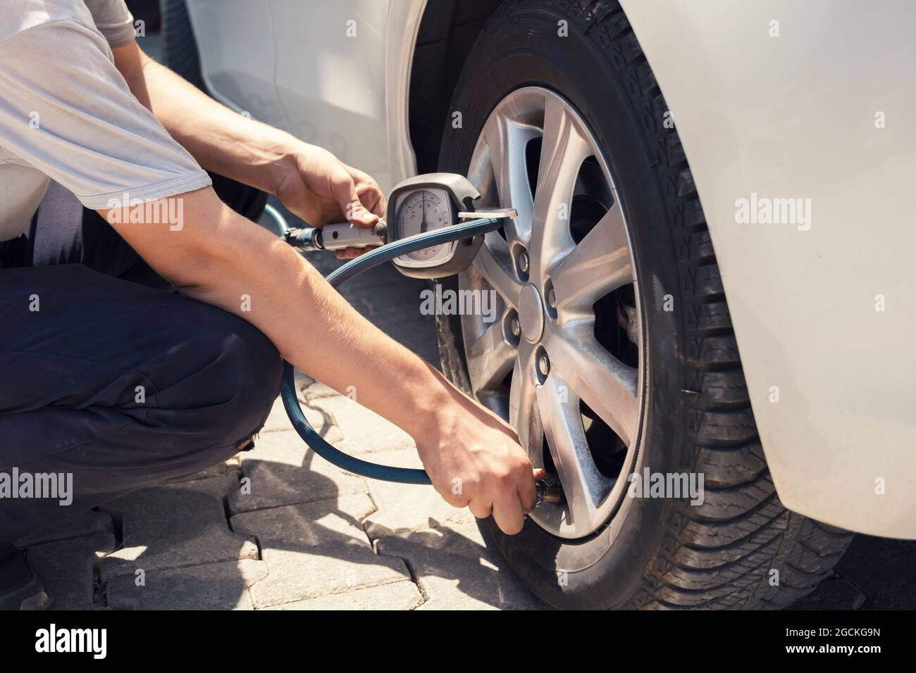 Close up mechanic inflating tire hand holding gauge pressure for