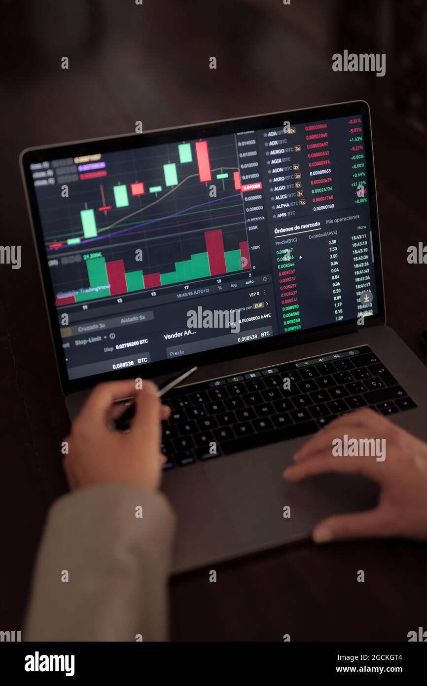 High angle of crop anonymous trader using netbook while analyzing chart on binary option Stock Photo
