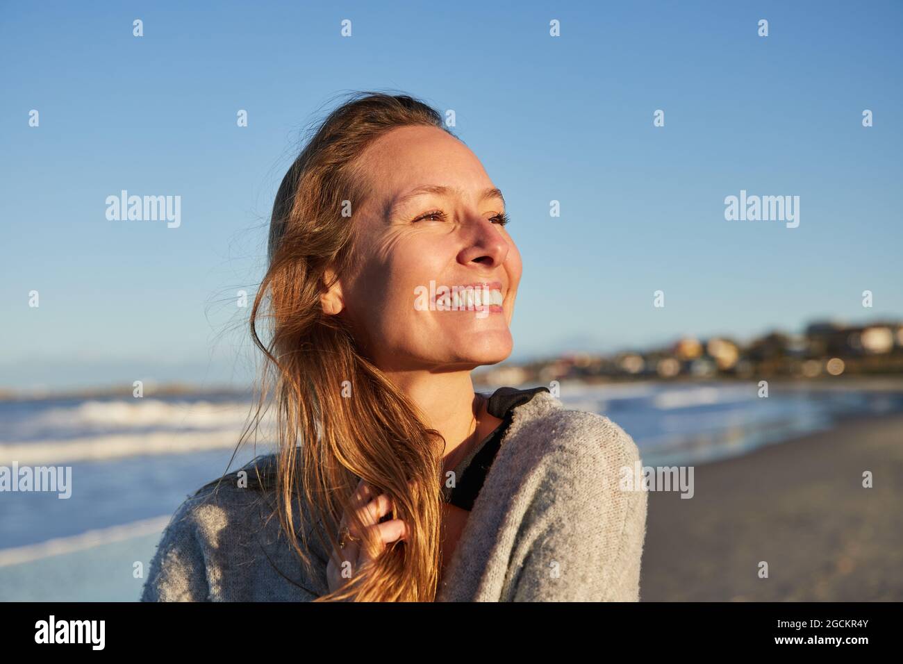 Charming young lady showing gun gesture and looking at camera in redness on blue background Stock Photo