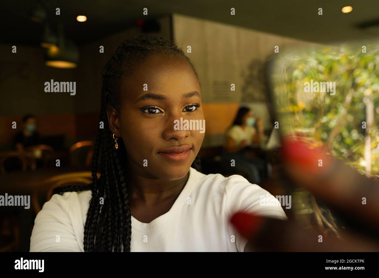 Charming African American female with braids taking self shot in cafe ...