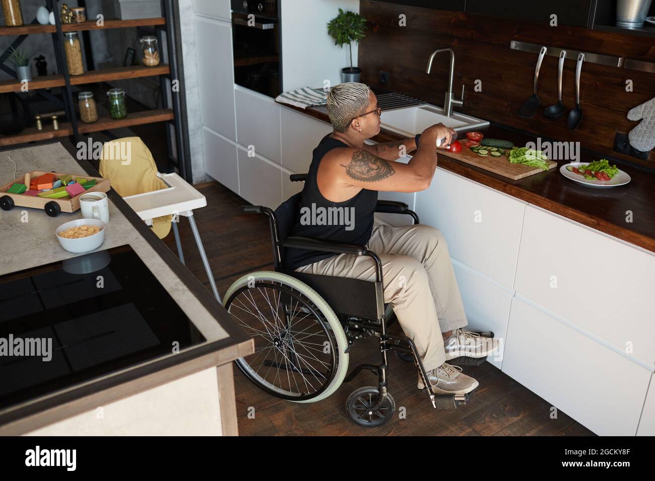 https://c8.alamy.com/comp/2GCKY8F/high-angle-portrait-of-contemporary-tattooed-woman-in-wheelchair-cooking-salad-at-home-in-kitchen-copy-space-2GCKY8F.jpg