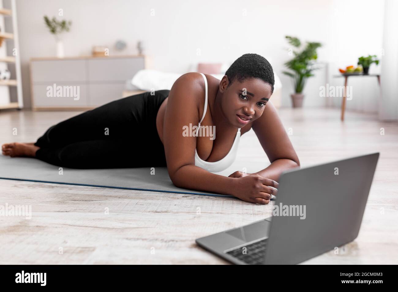 Premium Photo  Tired plus size black woman lying on yoga mat near laptop  wiping forehead after strength training at