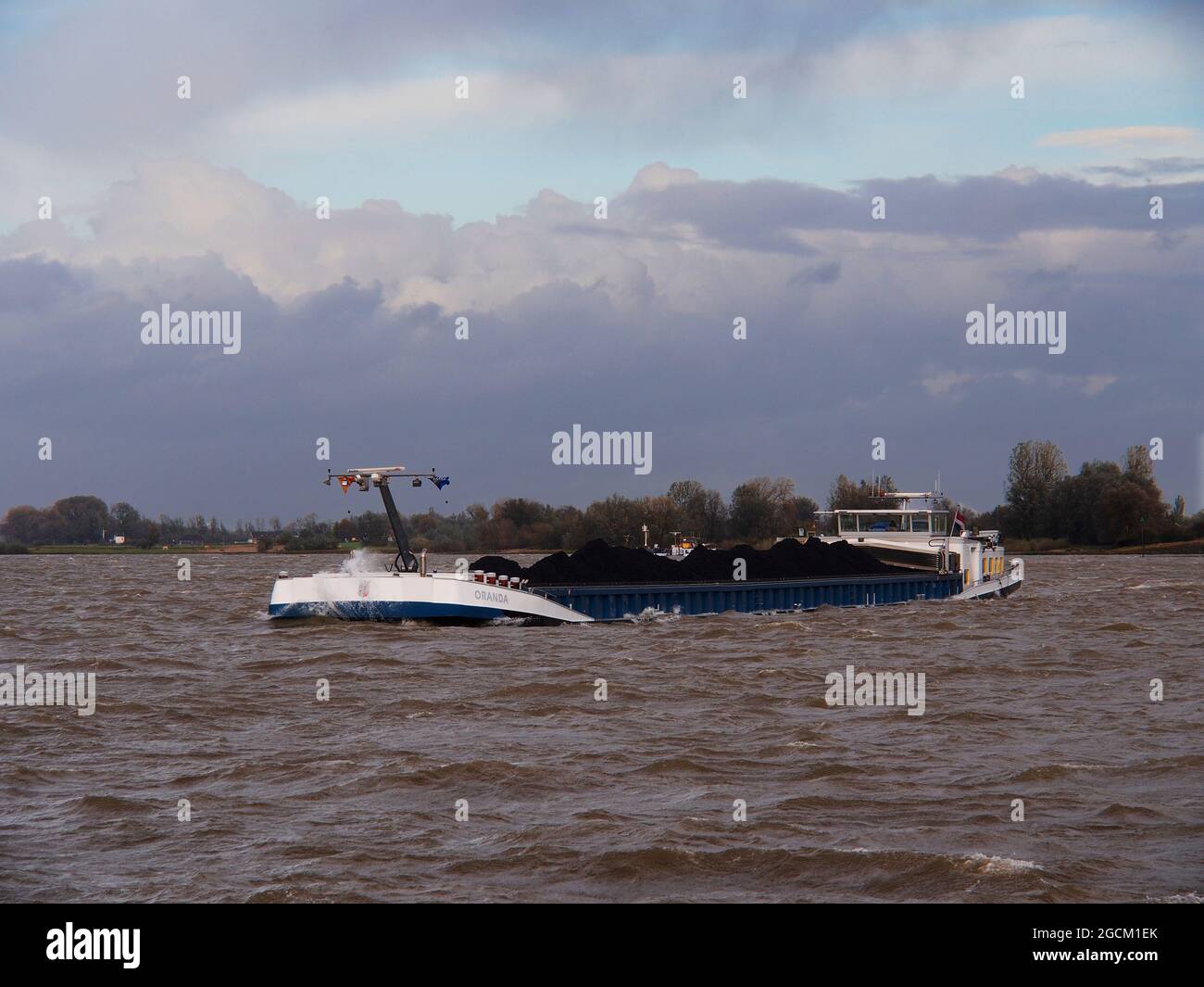 Commercial shipping on the River Rhine in Germany under blue dramatic skies Stock Photo