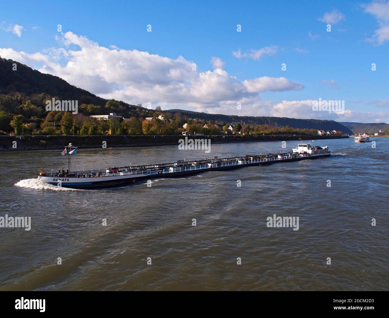 enormous commercial barge moving along the river rhine in Germany followed by a river cruise ship Stock Photo