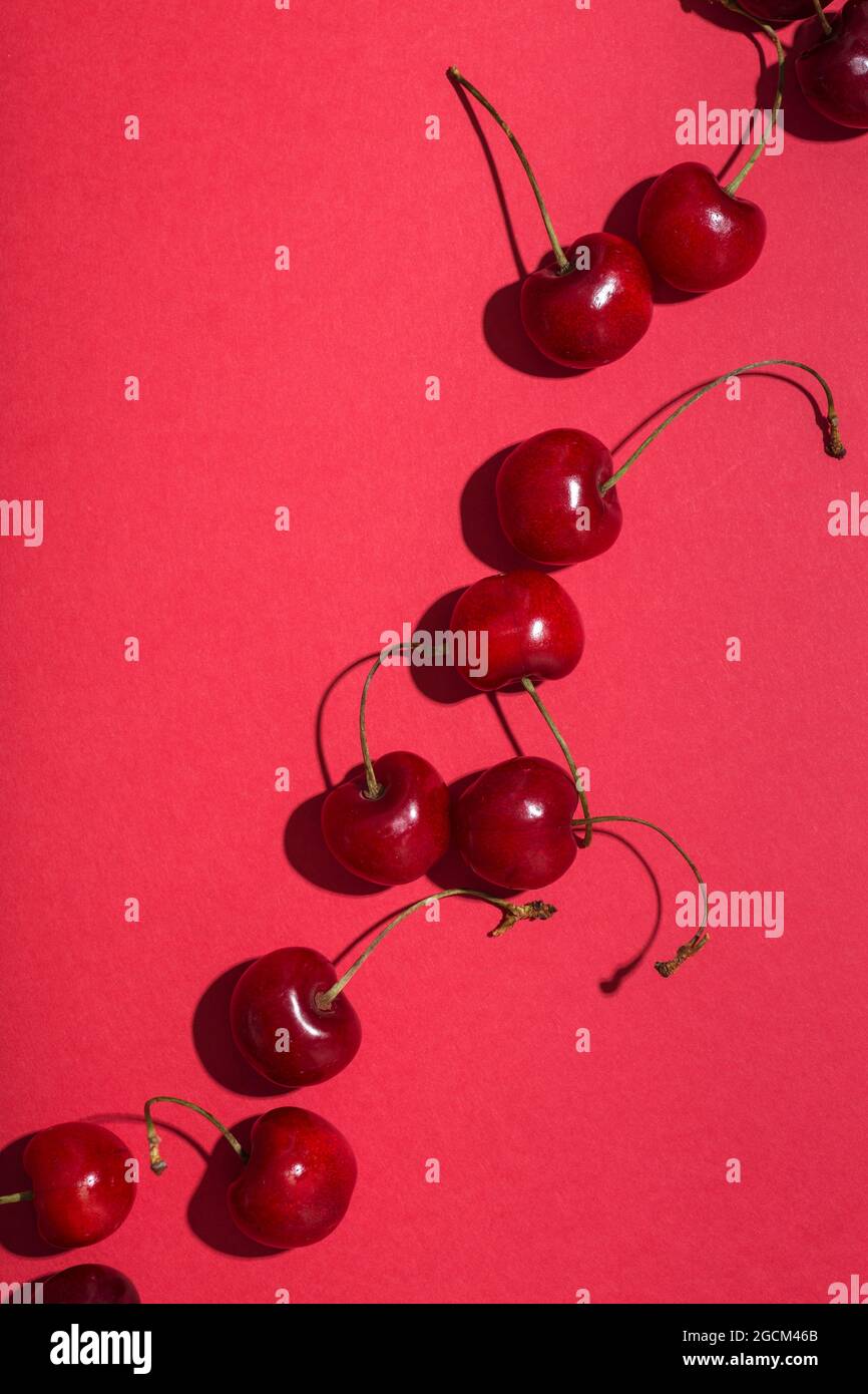 From above bright red appetizing cherries with stems on pink background Stock Photo