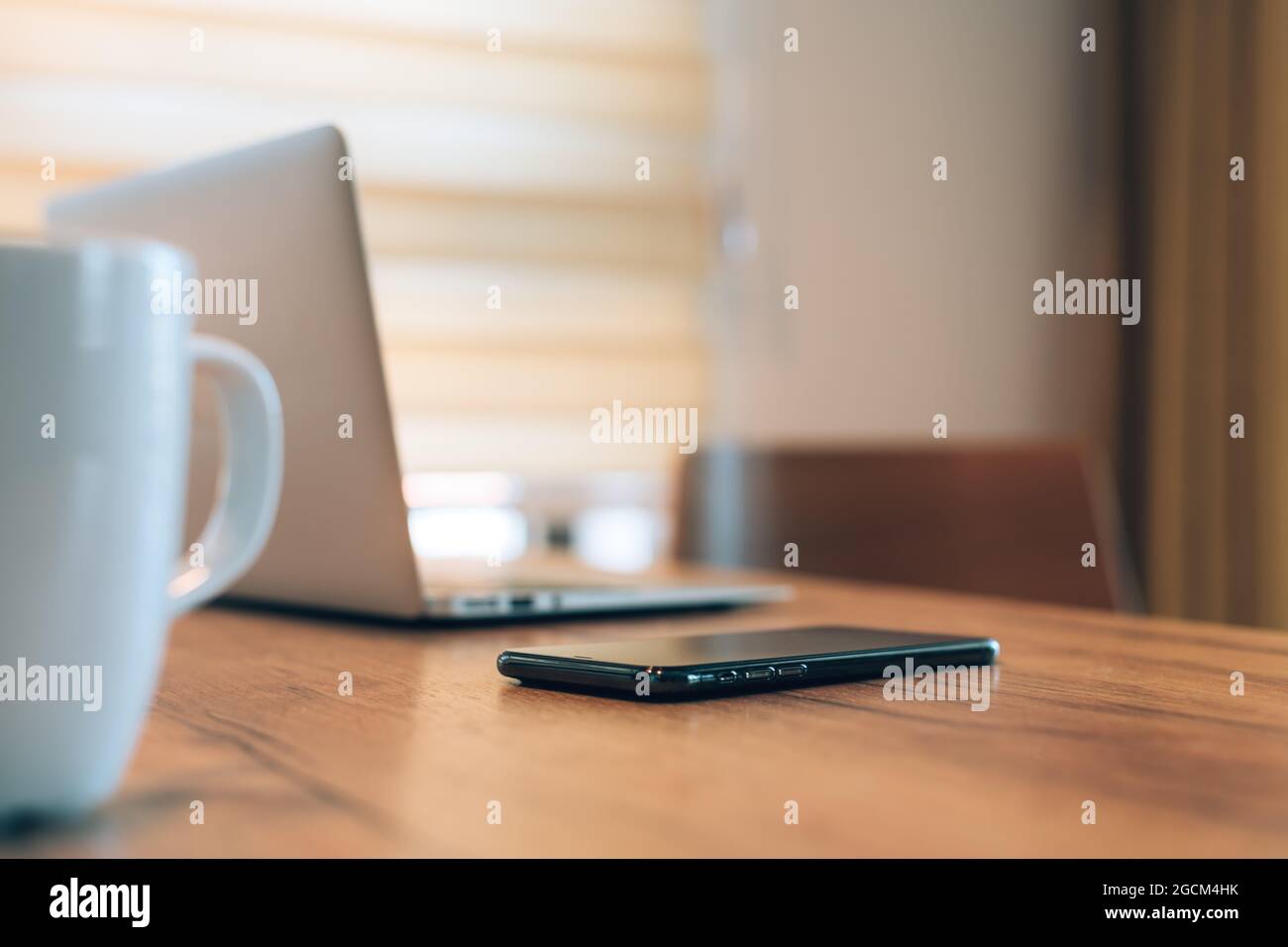 Mobile smart phone, laptop computer and coffee cup at home office workspace, selective focus Stock Photo
