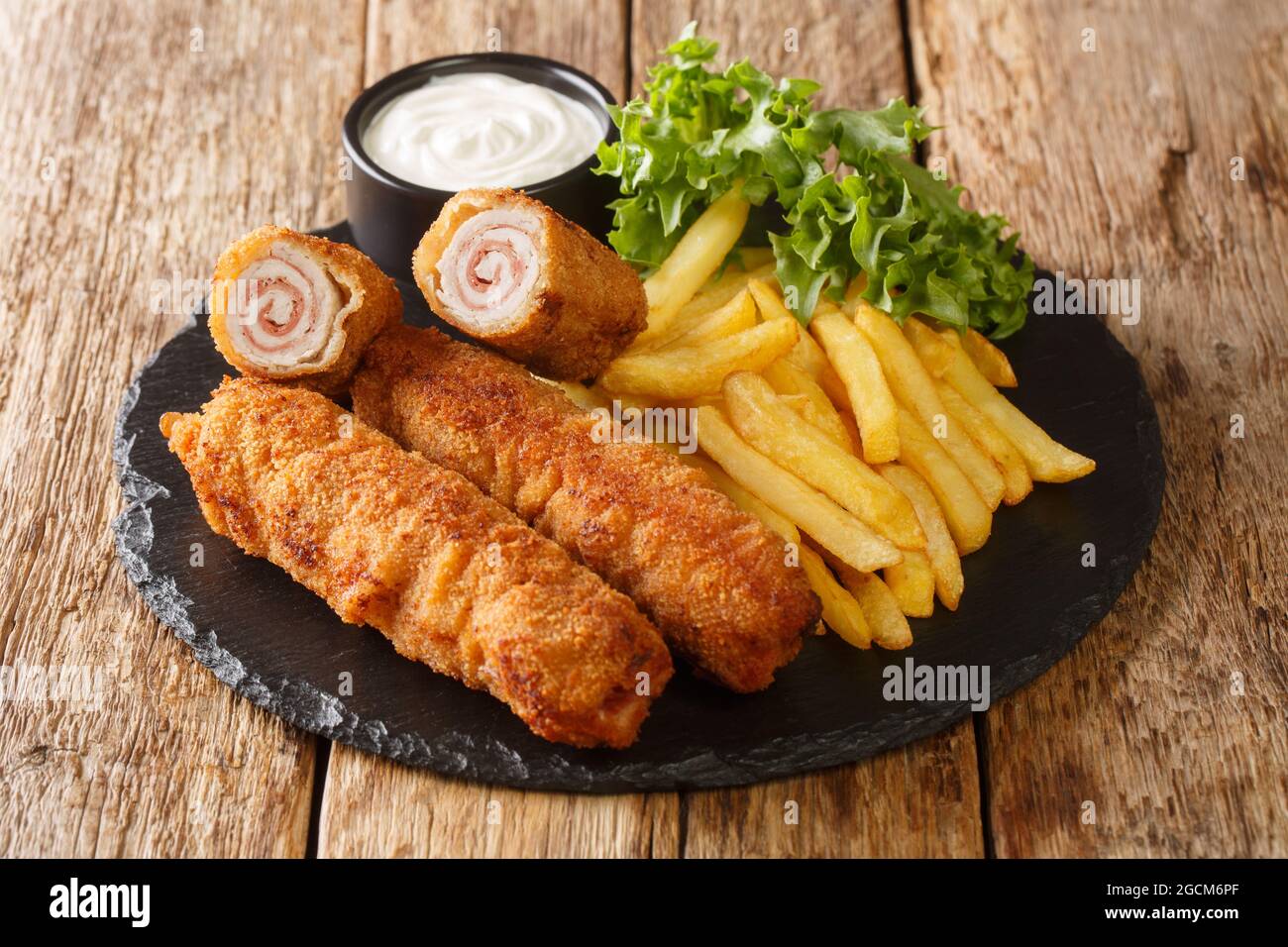 Flamenquin thin Pork Roll with Jamon served with French fries closeup in the slate plate on the table. Horizontal Stock Photo