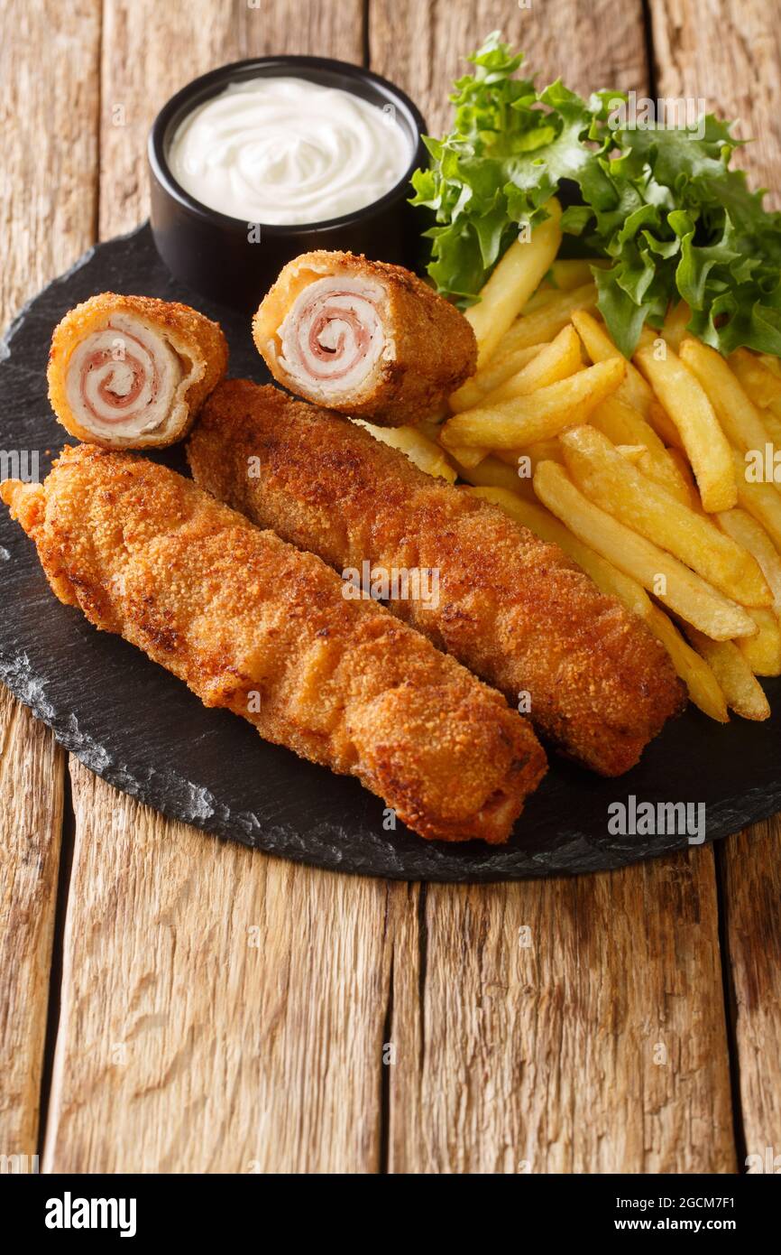 Andalusian Fried Pork Rolls Flamenquines with French fries closeup in the slate plate on the table. Vertical Stock Photo